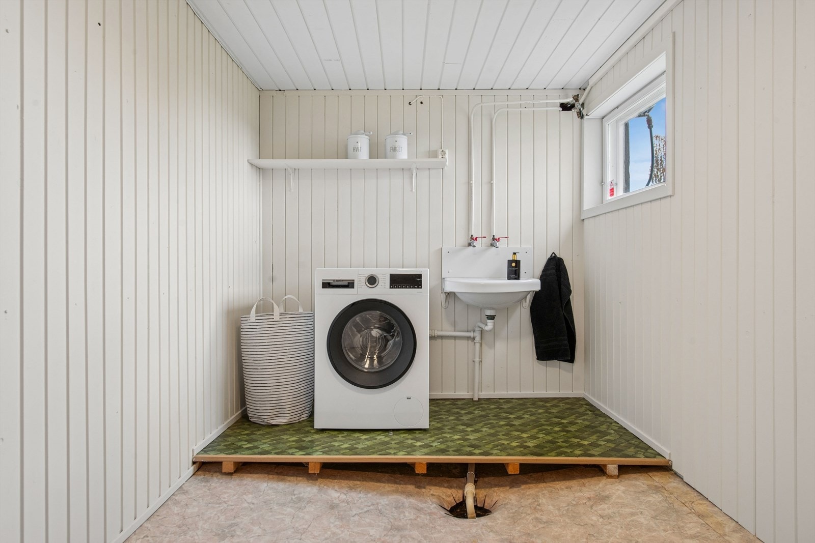 Funksjonelt vaskerom i underetasjen med våtromsbelegg på gulv og opplegg for vaskemaskin. Galleribilde