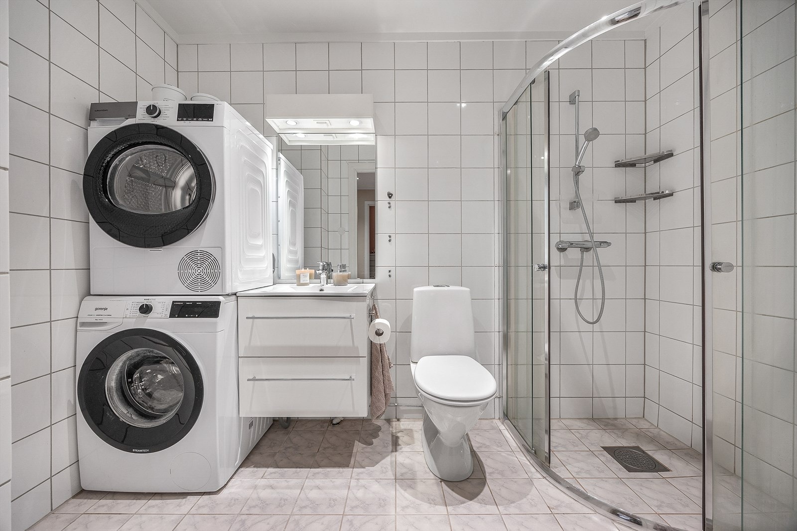 Badet er innredet med toalett, servant i baderomsinnredning, dusjhjørne og opplegg for vaskemaskin. Galleribilde