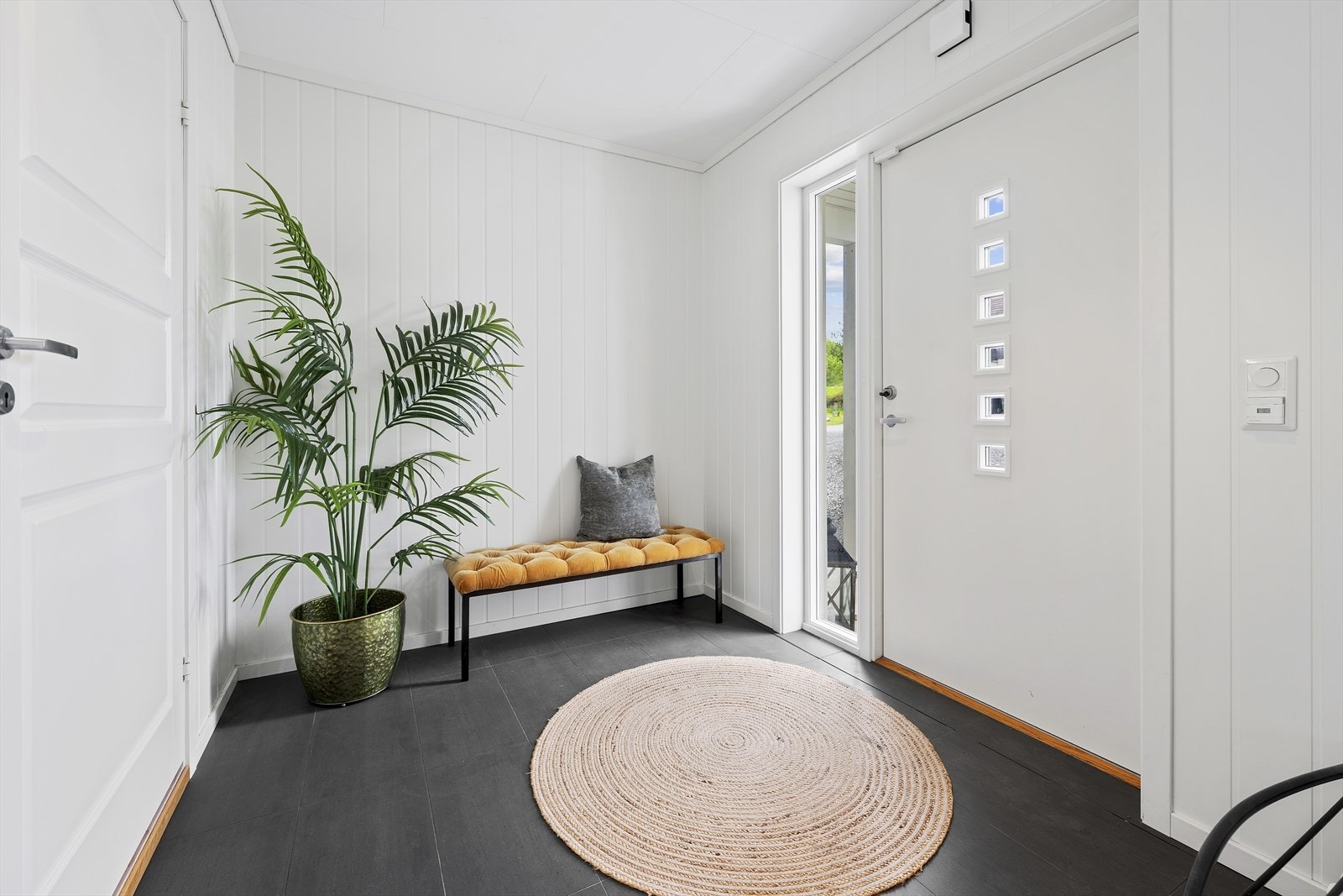Fra overbygget inngangsparti, trer du inn i en lys og romslig entré med flislagt gulv. I entréen er det god plass til sko og yttertøy Galleribilde
