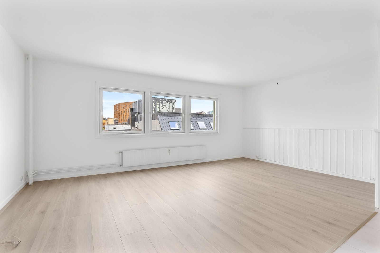 Leiligheten har en innbydende stue med 1-stavs laminatgulv og hvitmalte, slette overflater på vegger og i himling Galleribilde