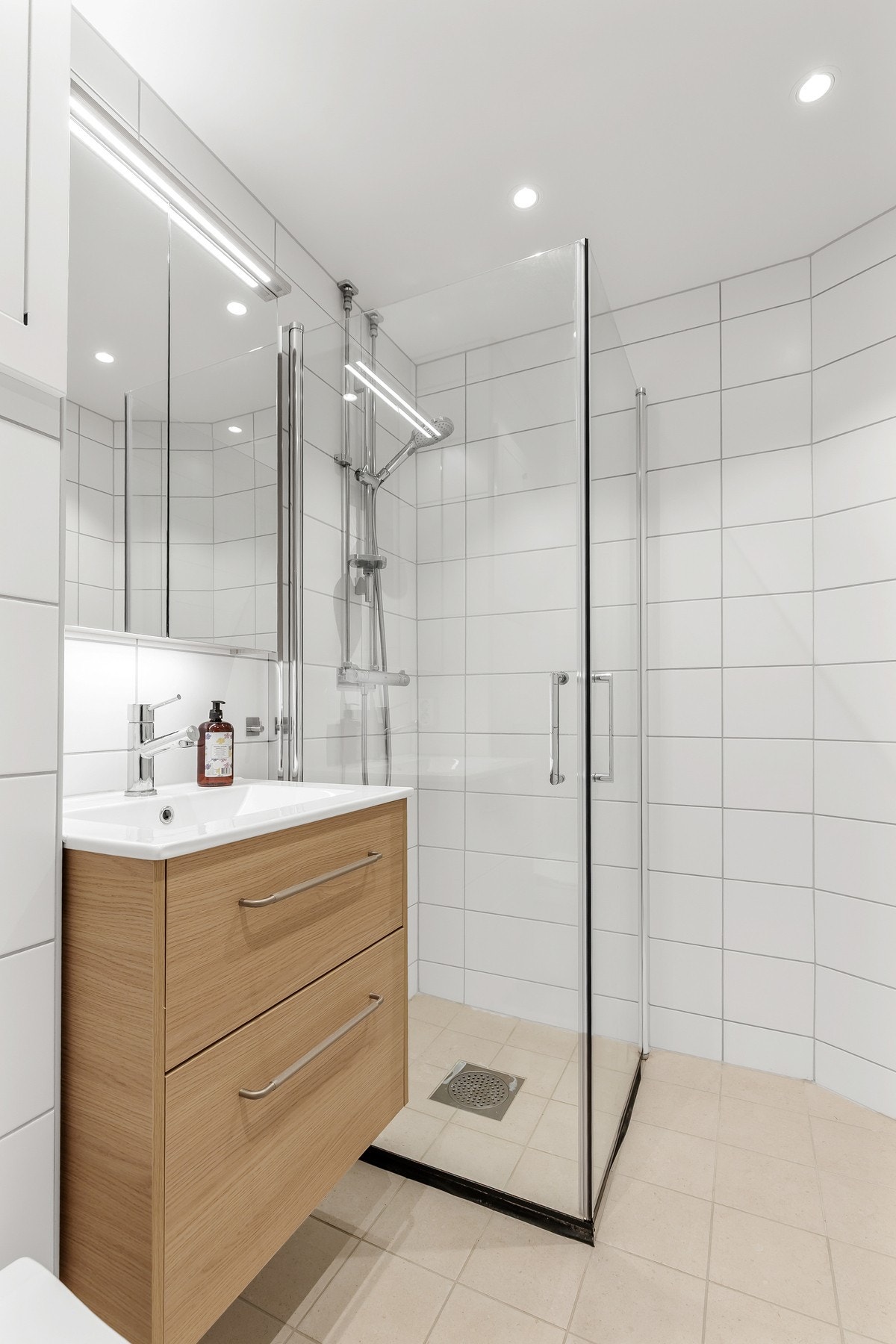 Badet er innredet med servantinnredning med heldekkende servant, speilskap med lys og dusjhjørne Galleribilde