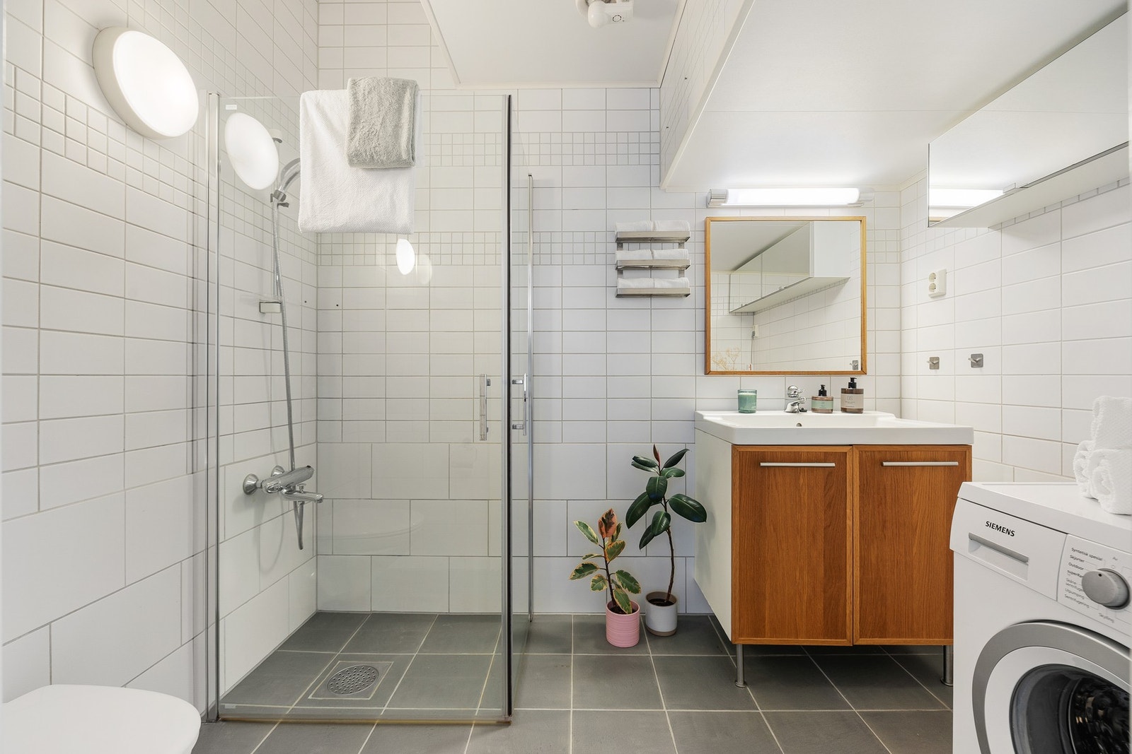 Badet ligger plassert praktisk til like ved inngangsdøren. Flislagt og pent bad i tidløse farger og materialvalg. Praktisk med innfellbare dusjdører. Galleribilde