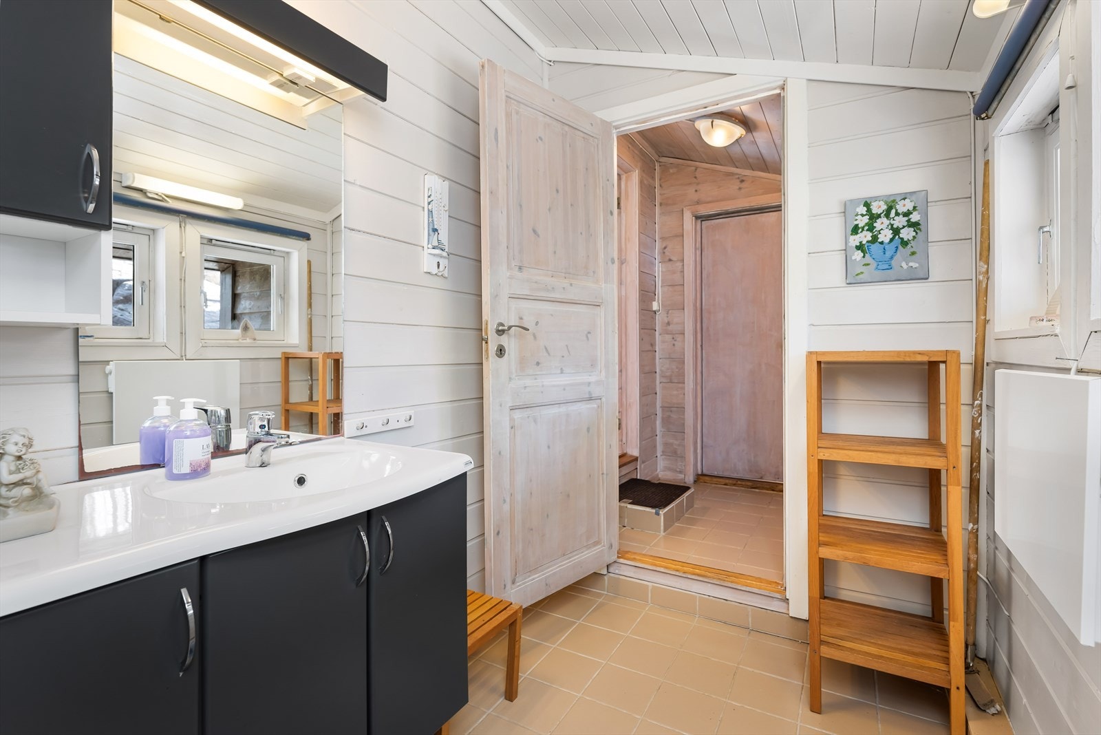 Baderom har fliser på gulv og tre på vegger, med flott baderomsmøbel, toalett og dusjkabinett. Galleribilde