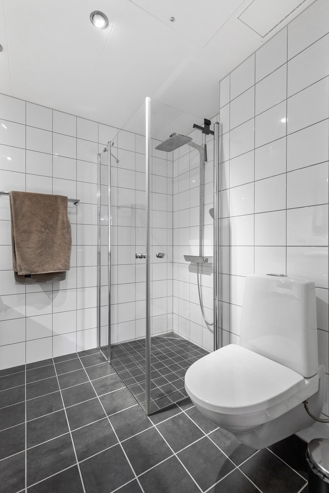 Badet er innredet med klosett, dusjhjørne med glassdører, servant med innredning og speil. Galleribilde