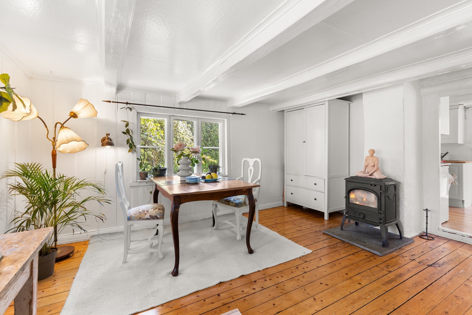 Lys og lun spiseplass med malte overflater, originale tregulv og vedovn som gir rommet en varm og innbydende karakter. Galleribilde