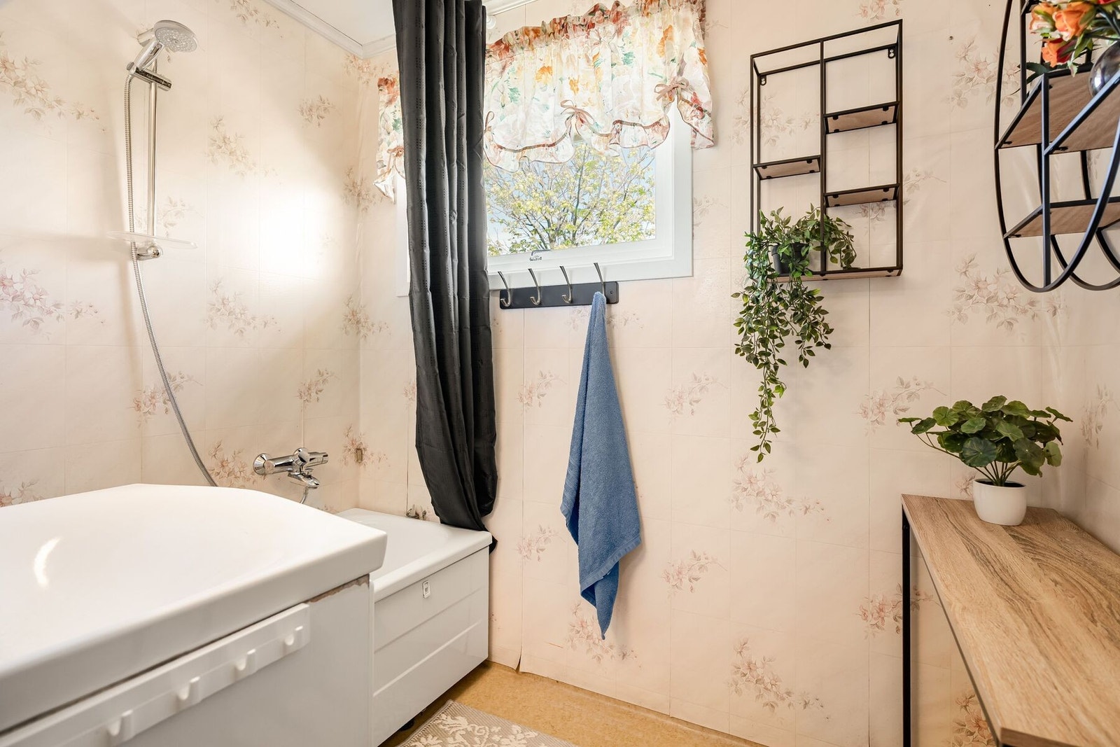 Badet er utstyrt med badekar med dusj og servant i innredning Galleribilde