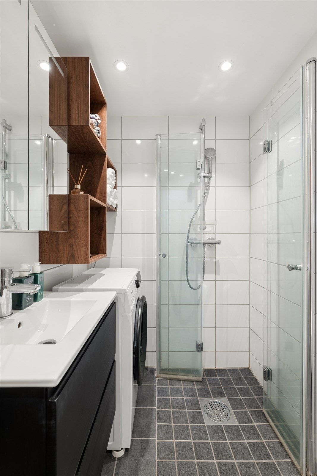 På gulvet er det lagt varmekabler og i taket er det downlights. Innredning består av servant med skuffeseksjon, speilskap med overlys, vegghengt klosett, dusjhjørne med foldedører og opplegg for vaskemskin. Galleribilde