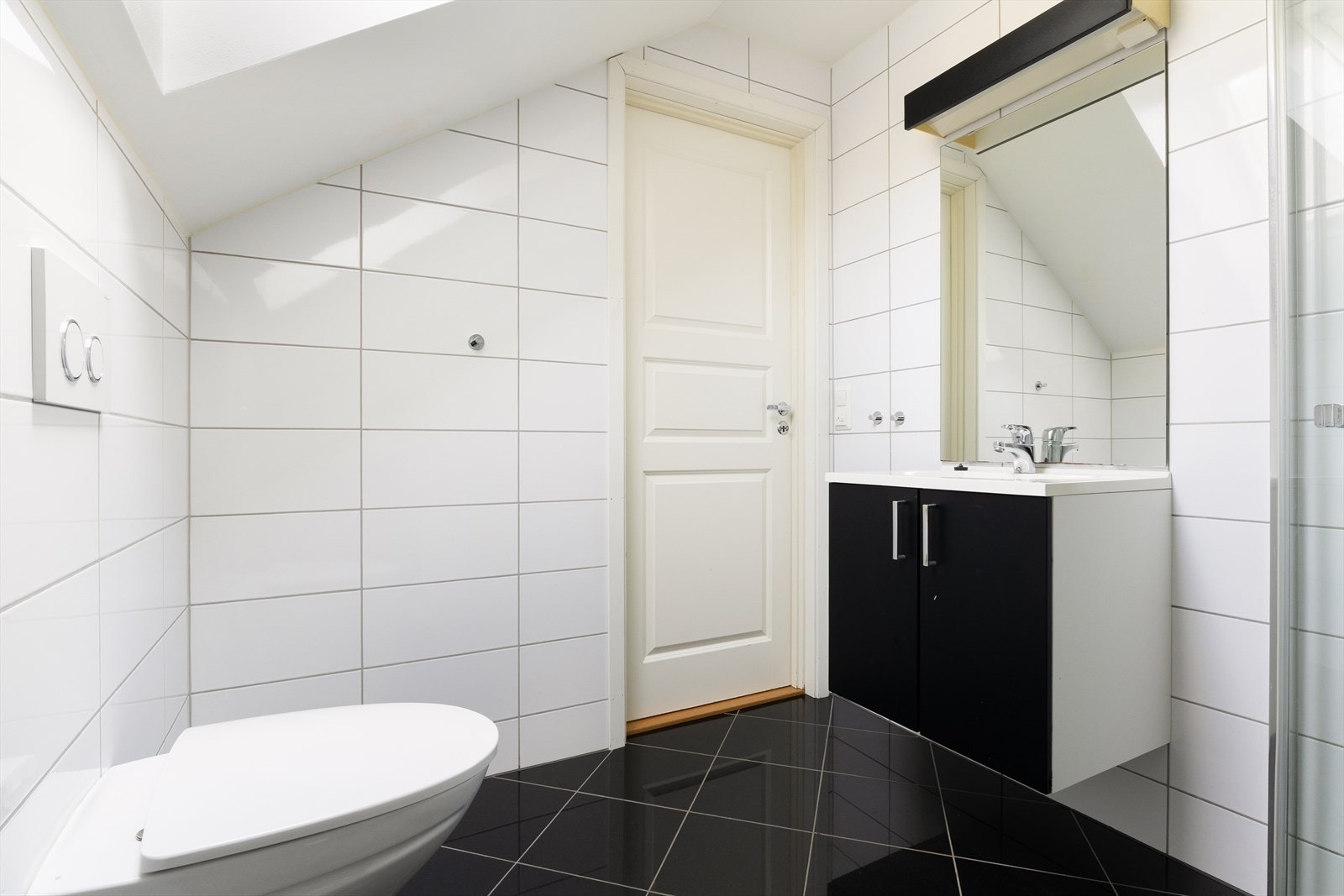 Badet i 2. etasje er også helfliset og utstyrt med vegghengt toalett, helstøpt servant med skuffer under, dusjdører i klart glass og opplegg for vaskemaskin Galleribilde
