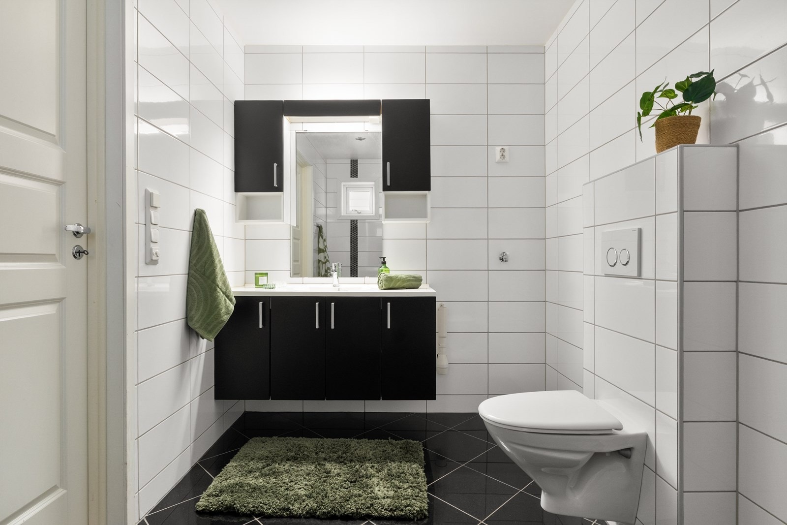 Badet i 1. etasje er romslig og innredet med vegghengt toalett, helstøpt servant med over- og underskap, samt opplegg for vaskemaskin. Galleribilde