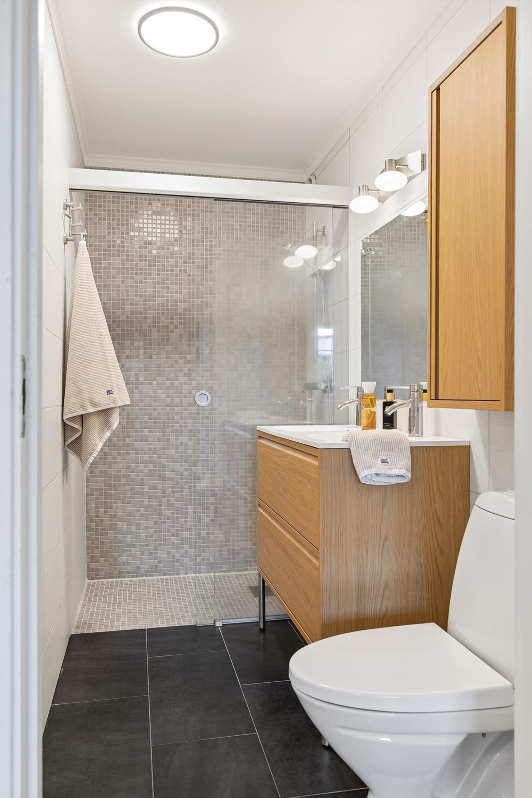 Badet i underetasjen er opprinnelig en del av et tidligere vaskerom, som senere er delt opp og omgjort til et bad. Fliser på gulv og vegger. Galleribilde