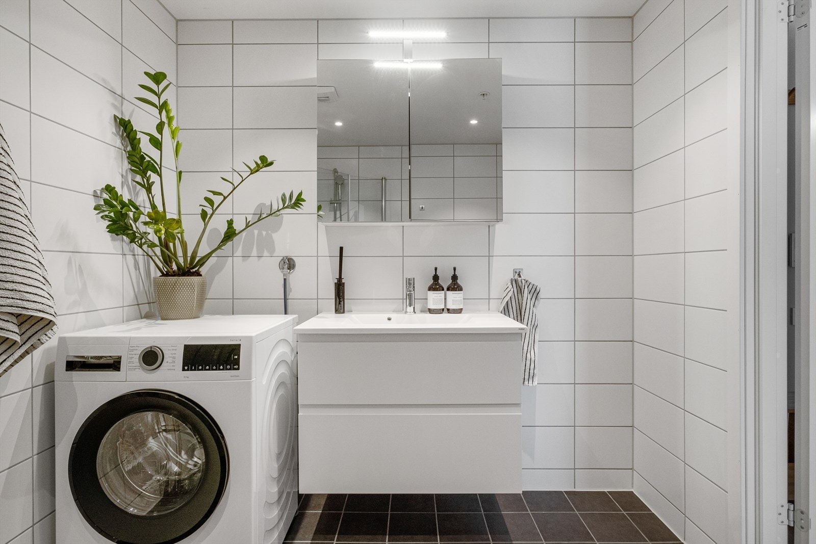 Badet er innredet med nedfelt servant, speil med belysning, dusjhjørne med håndholdt armatur og vegghengt toalett. Galleribilde