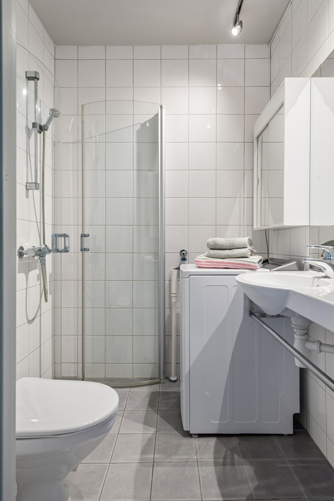 Badet har flislagte overflater på gulv og vegger, dusjhjørne og toalett. Galleribilde