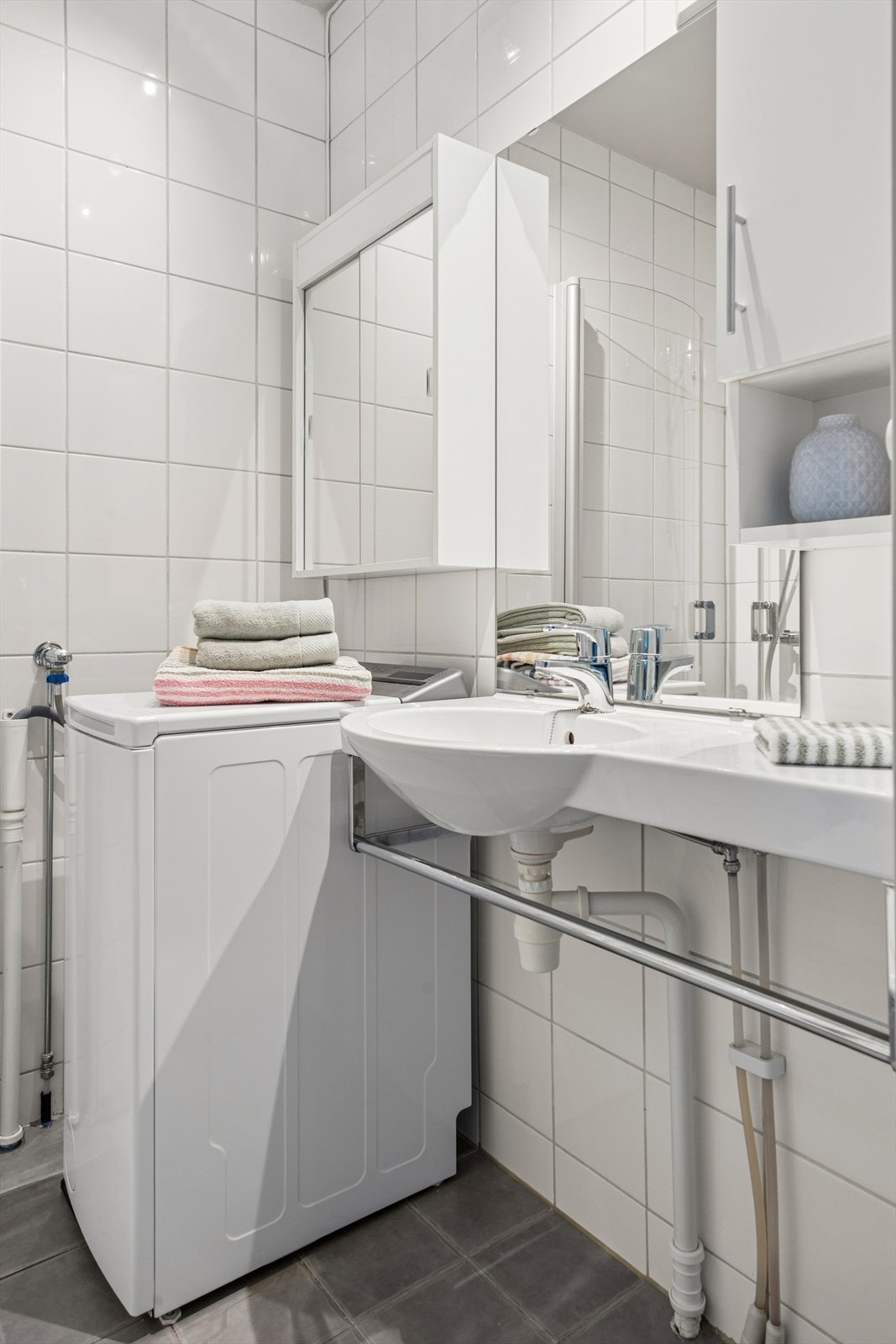 Praktisk innredet bad med servant og opplegg for vaskemaskin. Galleribilde