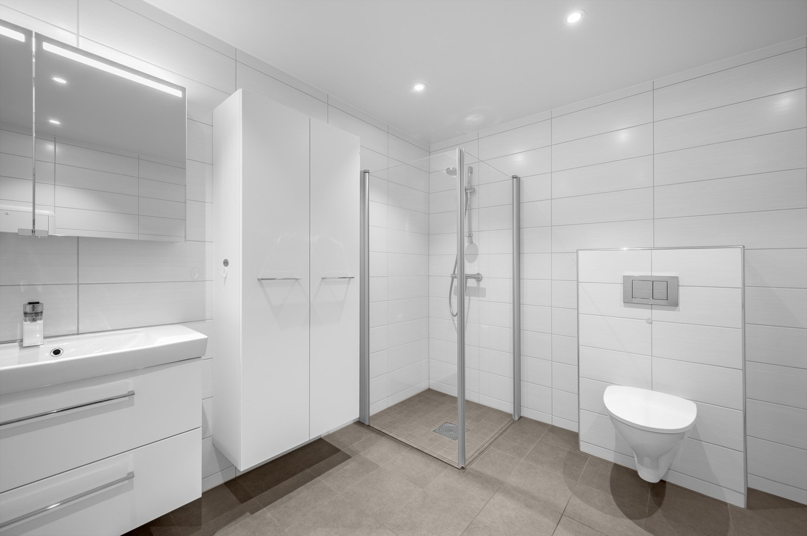 Badet er innredet med dusjhjørne som har svingbare glassdører, vegghengt toalett og servantinnredning. Opplegg for vaskemaskin under benkeplate hvor varmtvannsbereder (ca. 120l) er plassert. 2 stk. høyskap på vegg Galleribilde