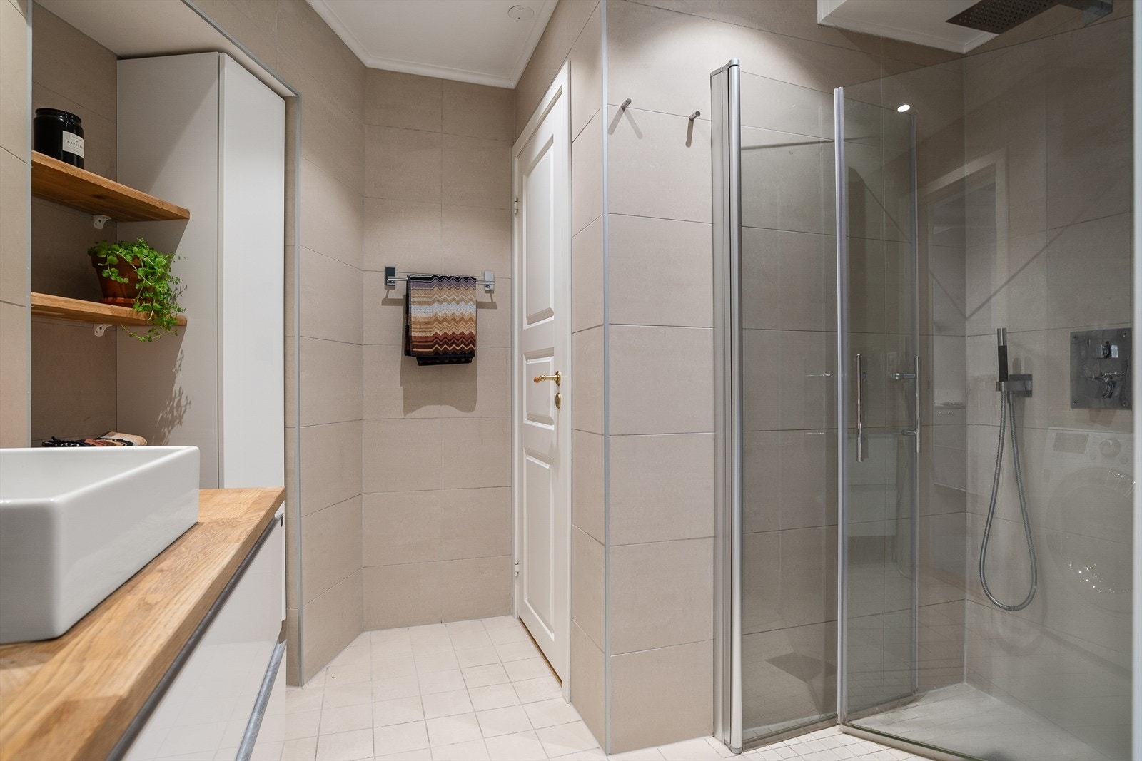 Pent flislagt bad med varmekabler i gulv, fra 2016. Badet har lyse fliser, stor innfellbar dusjnisje, vegghengt wc, godt med skapplass og opplegg for vaskemaskin/tørketrommel. Galleribilde