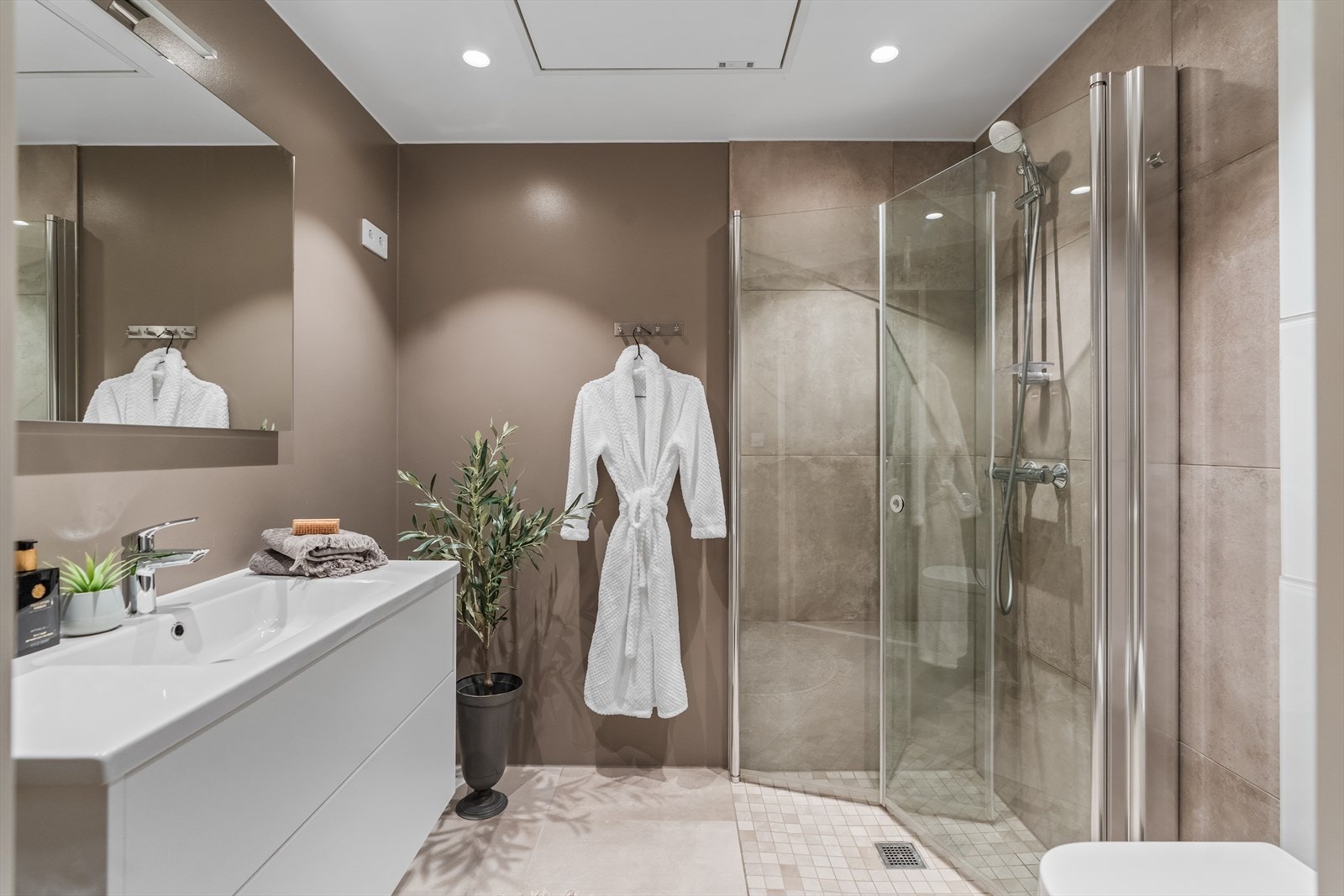 Badet er delikat utført med beige fliser på gulvet, gråbeige fliser på veggene i dusjsonen og ellers slette, malte vegger i en matchende beigetone. Galleribilde
