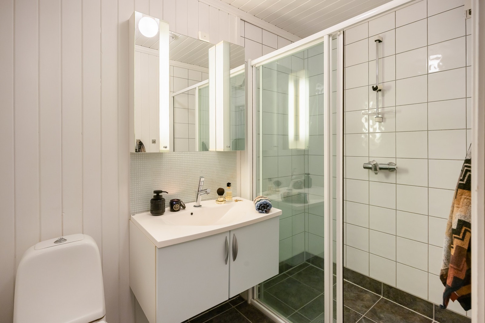 Badet er på 3,5m² og har fliser på gulv og i dusjnisje. Her er baderomsinnredning, toalett og dusjnisje. Varmekabler i gulv. Galleribilde