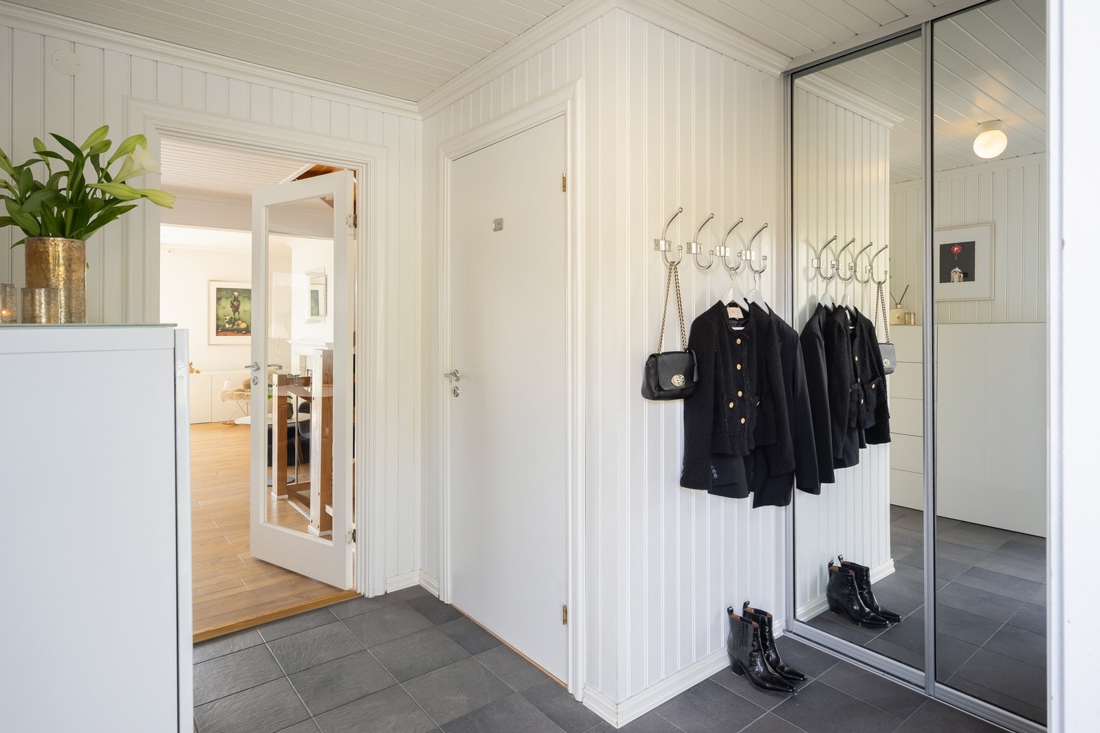 Man kommer inn i en romslig flislagt gang utstyrt med skyvedørsgarderobe. Varmekabler i gulv. Galleribilde