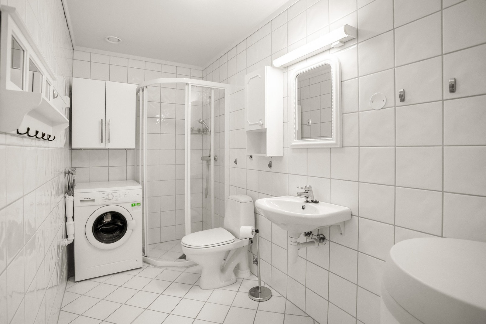 Badet er innredet med servant med speil og skap, toalett, dusjhjørne/dusjvegger samt opplegg for vaskemaskin. Galleribilde