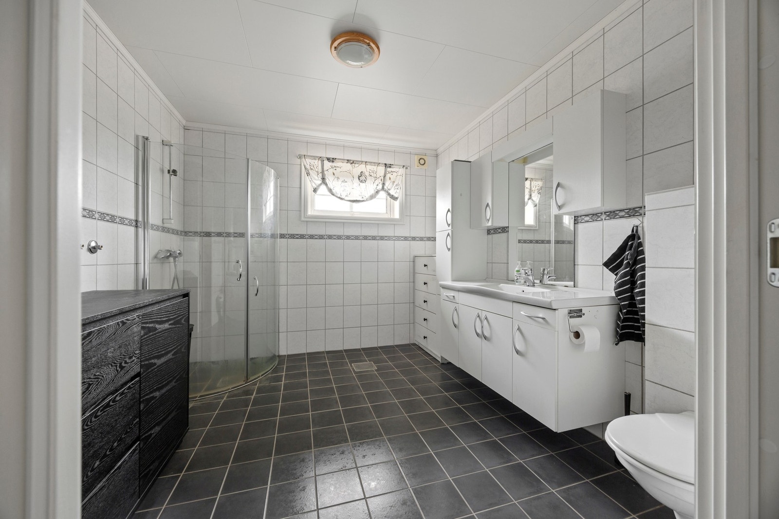 Badet er flislagt og har varme i gulv. Utstyrt med dusj, toalett og servantskap. Galleribilde