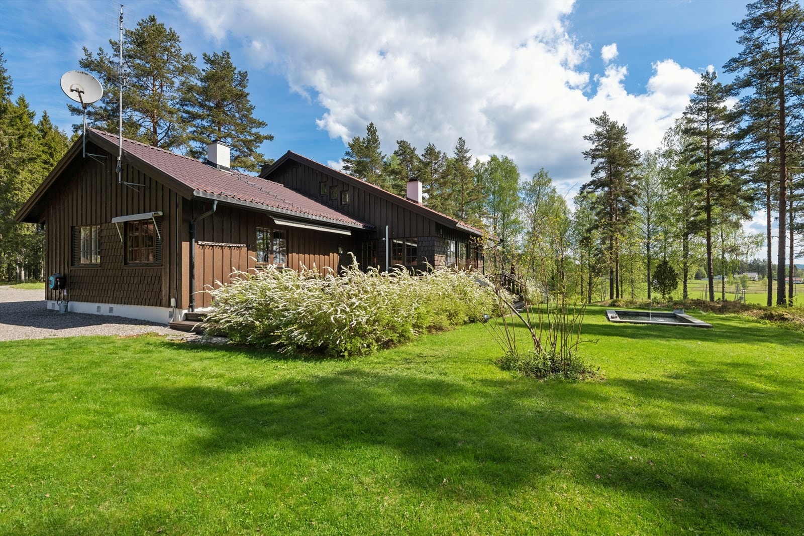 Tomten er meget pent opparbeidet med beplantning, plen og noen større trær. Galleribilde