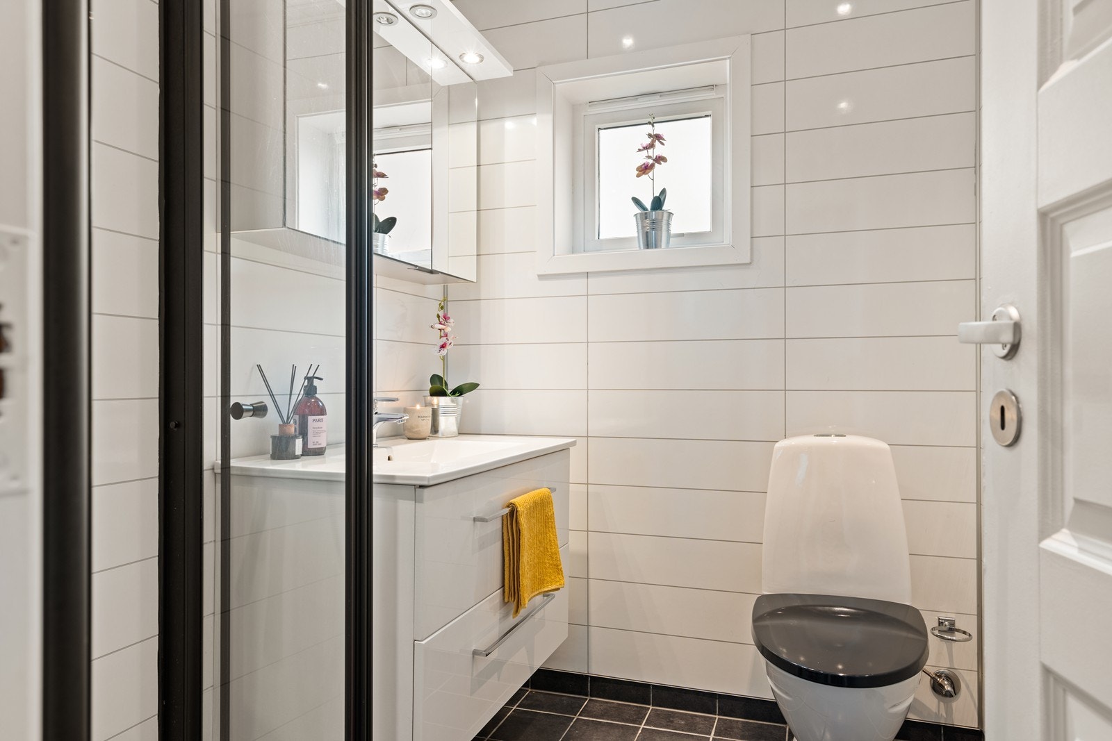 Bad med varmekabler og flislagt gulv, dusjnisje med regnvannsdusj og glassdører, spotter i tak, baderomsinnredning, speilskap med int. spotter, moderne vask og wc. Galleribilde