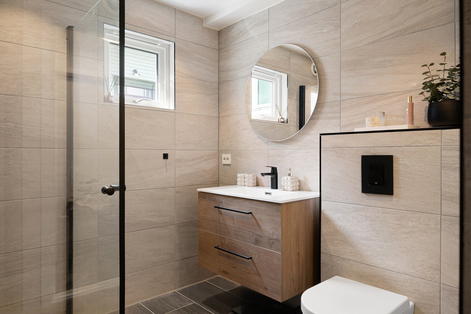 Lekkert helfliset bad fra 2023 med varmekabler i gulv. Badet er innredet med nedfelt servant i skuffeseksjon, veggmontert toalett og dusjvegger/hjørne. Galleribilde