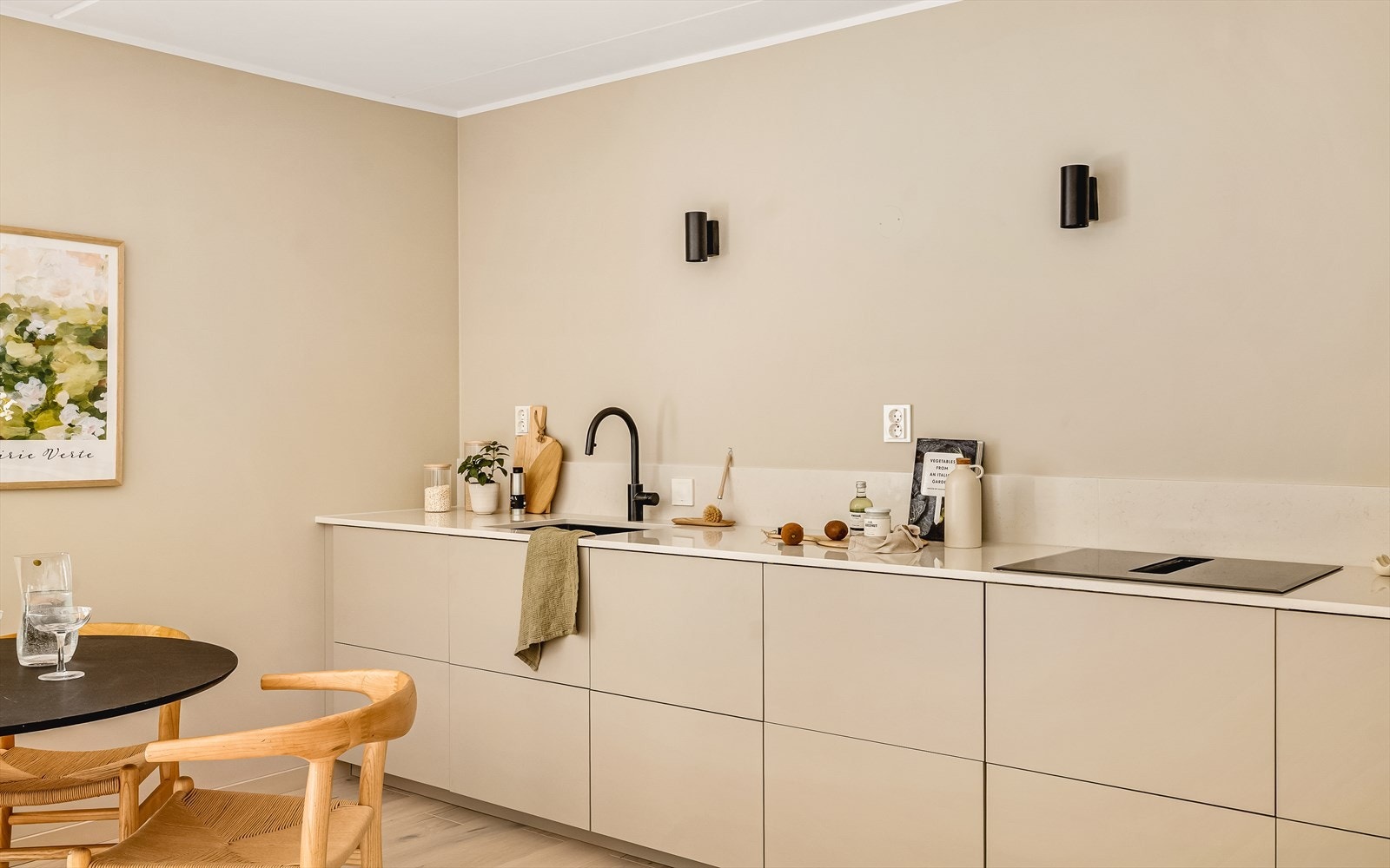 Innredning med slette fronter i beige utførelse, med benkeplate i stein fra Silstone. Platetopp med integrert ventilator. Galleribilde