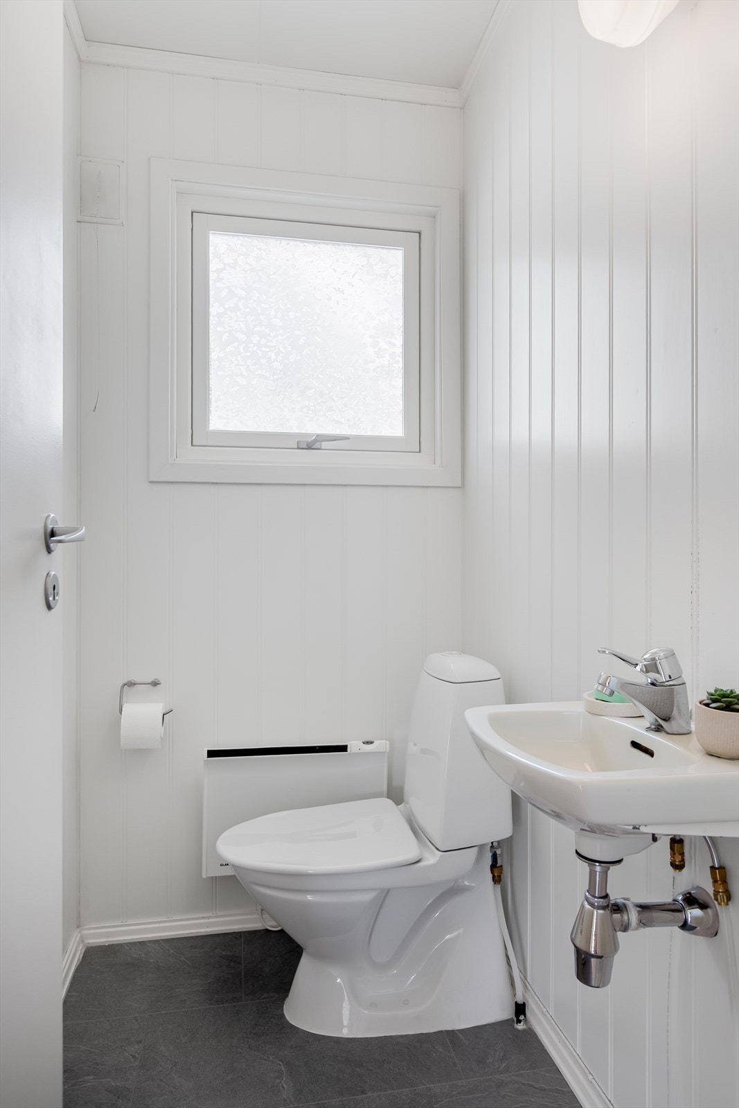 Nær badet er det et lyst, oppusset toalettrom med wc og vegghengt servant. Galleribilde