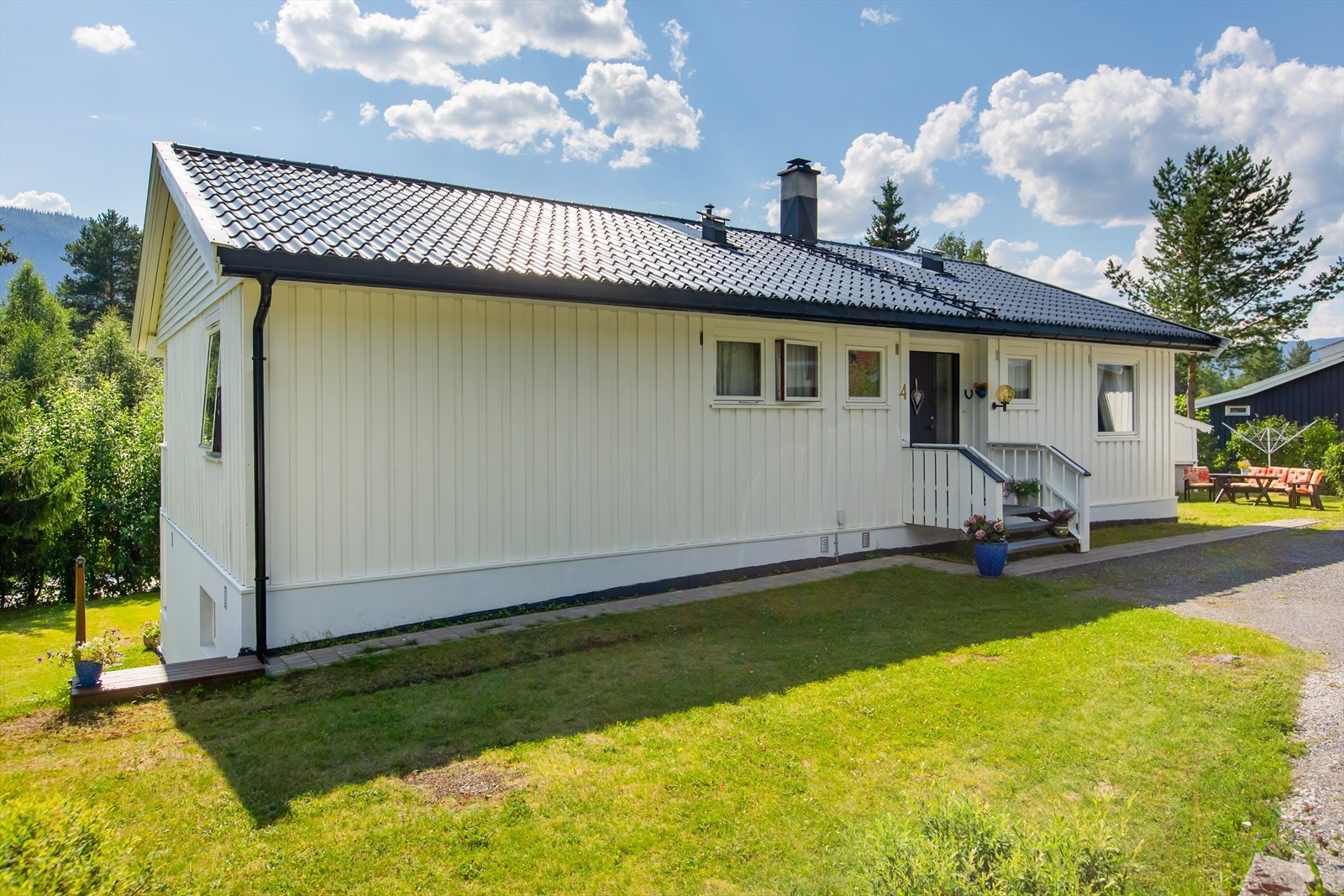 Boligen ligger på en pent opparbeidet eiertomt med fine plener og beplantning over to nivåer. Det er trapp med rekkverk mellom de to nivåene. Galleribilde