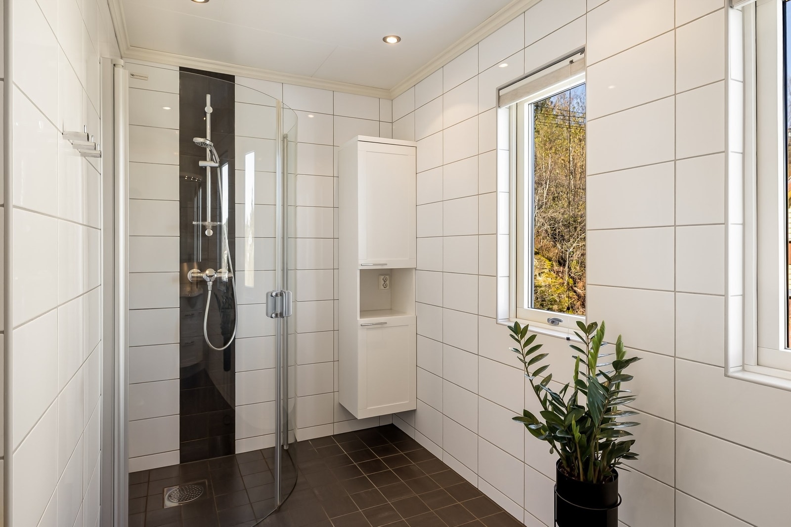Badet har gulvvarme for økt komfort og en romslig dusjnisje med innfellbare glassdører. Galleribilde