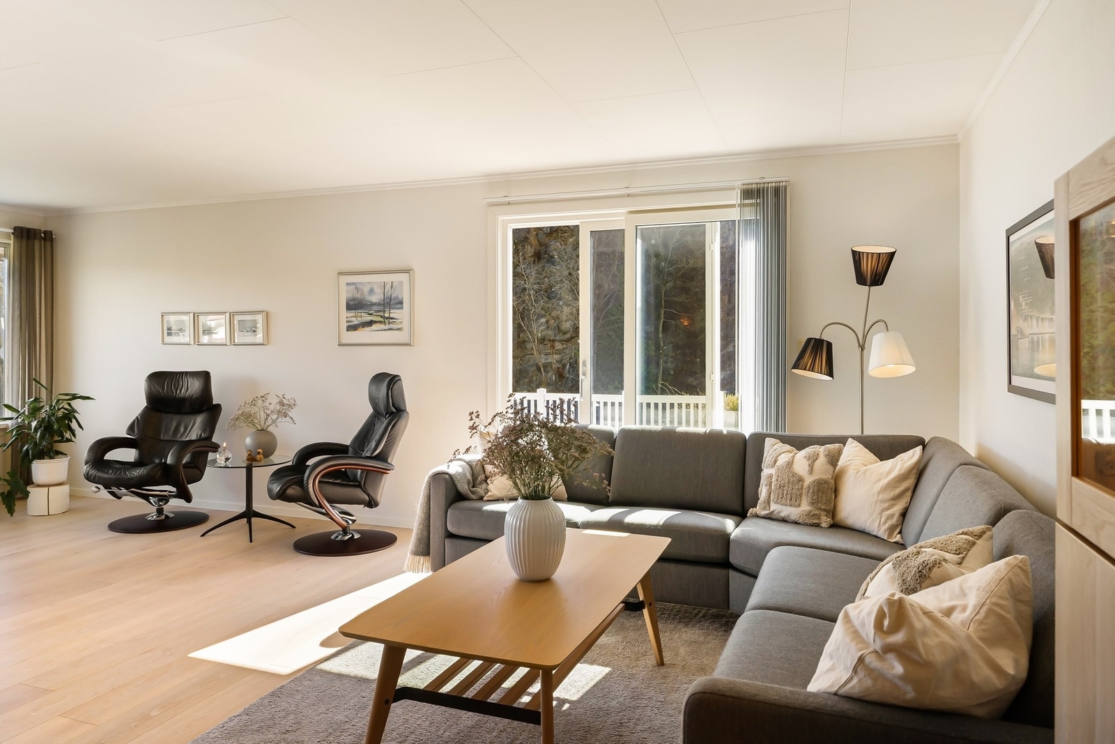 Her ser man tydelig hvordan stuen kombinerer en lun sofakrok med en lys, åpen sone mot utsikten og terrassen. Galleribilde