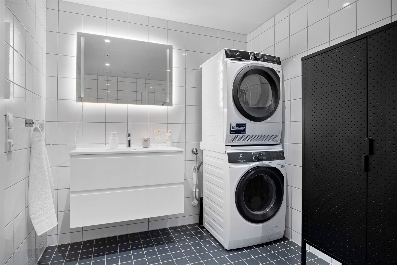 Lyst og lekkert bad med plass for vaskemaskin og tørketrommel. Flislagte gulv og vegger. Galleribilde