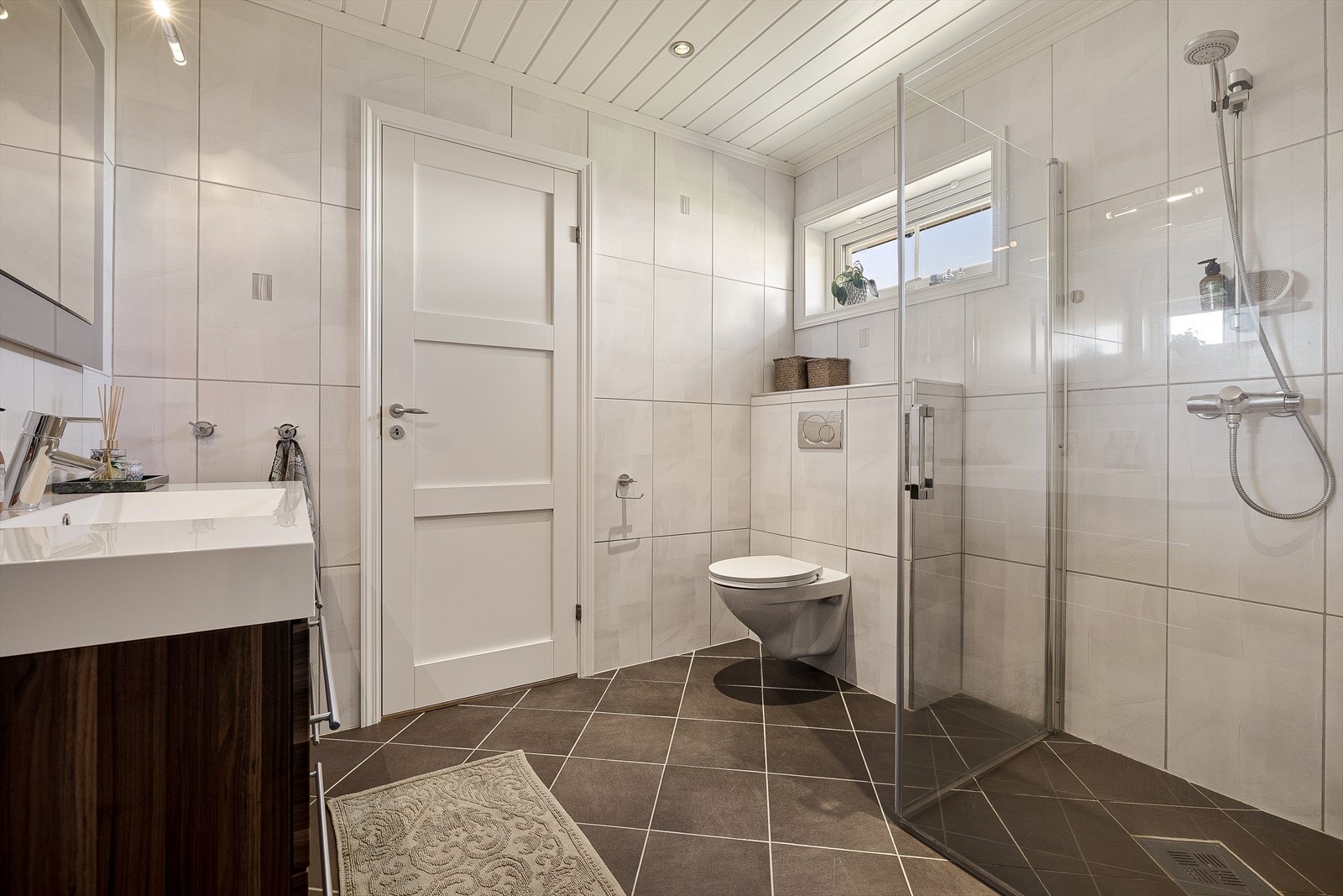 Det andre badet, i tilbygget fra 2007, har flislagt gulv med varmekabler og dusjhjørne. Galleribilde
