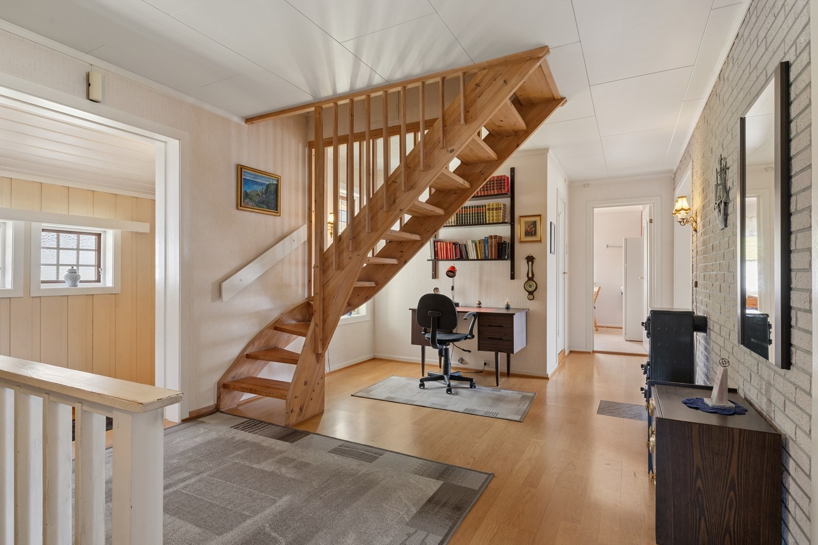 Herfra er det trapp opp til loftsetasjen, som gir enkel tilgang til boligens øvre nivå, samt trapp ned til kjelleren. Under trappen er det etablert en smart og plassbesparende kontorkrok. Galleribilde