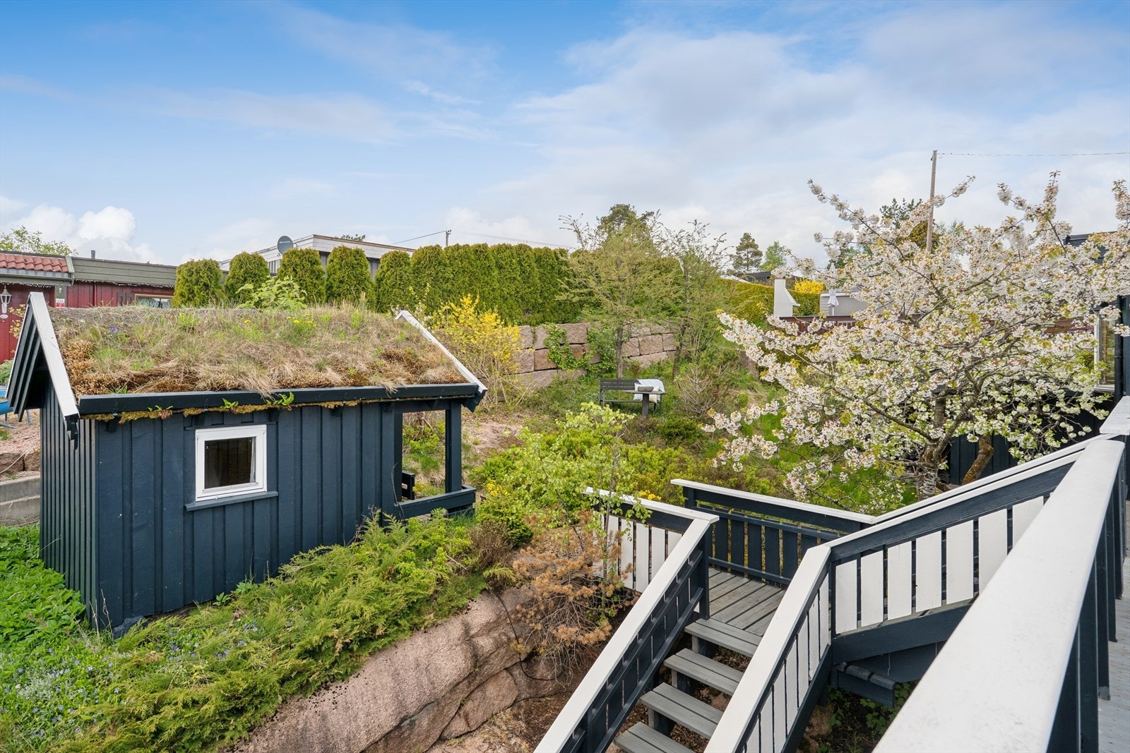 Pent opparbeidet naturtomt med trær, busker og beplantninger. I hagen er det også en dukkestue. Galleribilde