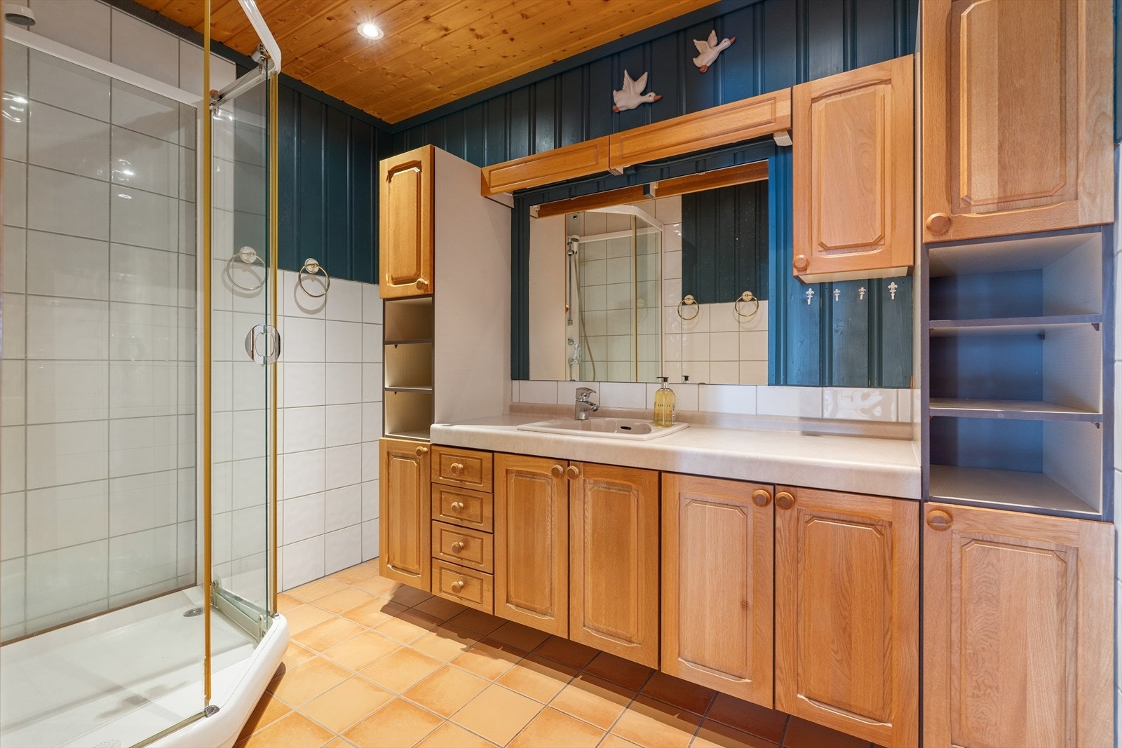 Badet i 1. etasje har flislagte overflater og gulvvarme. Det er også malt panel og himling med downlights. Rommet har dusjkabinett og servant med under- og overskap. På grunn av bemerkninger har rommet fått TG 3. Hulltaking påviser ingen unormale forhold. Galleribilde