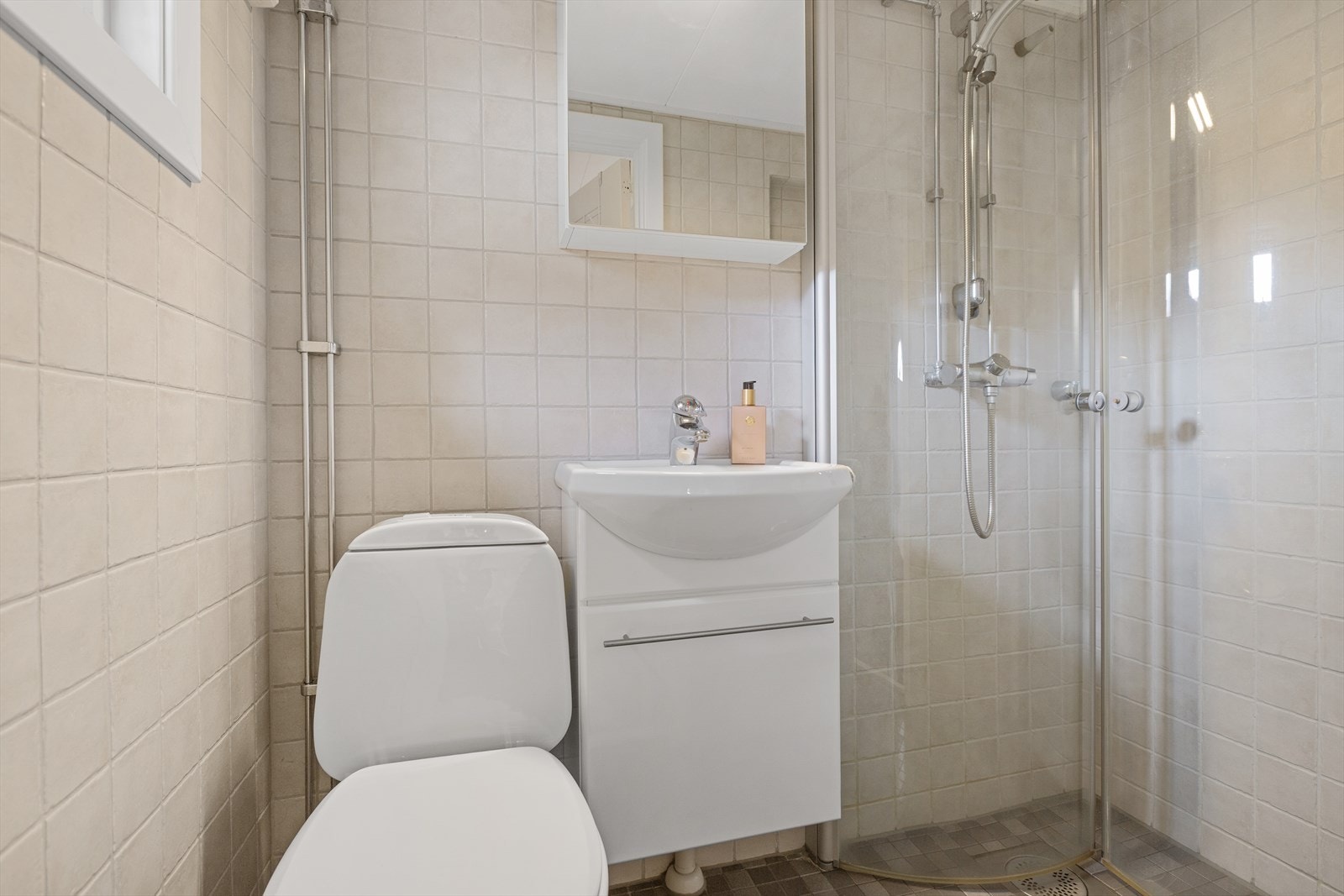 Flislagt bad fra 2012 som har gulvvarme. Badet er utstyrt med toalett, dusj med glassdører, samt baderomsinnredning med servant og speilskap. Galleribilde