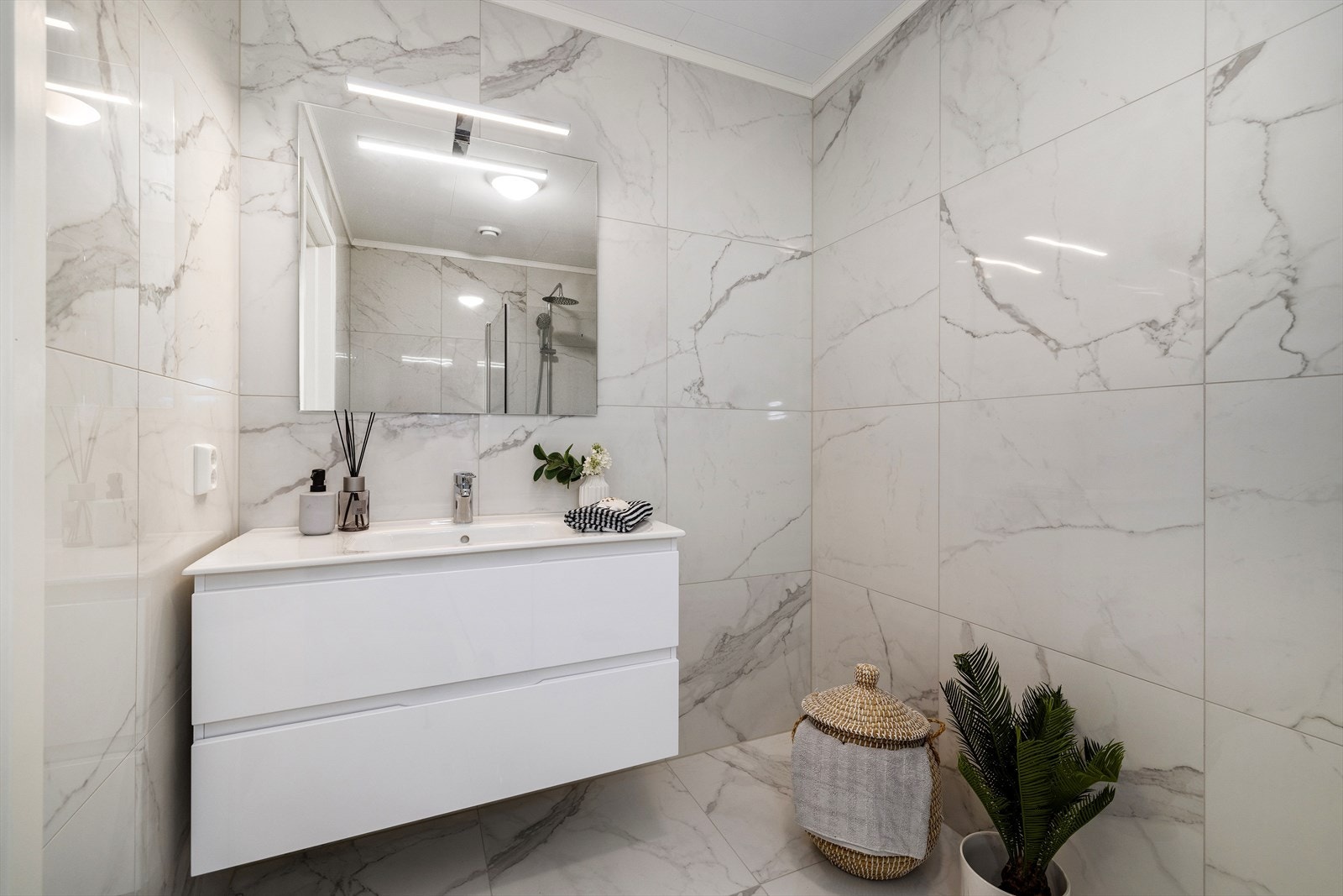 Badet har stilrene overflater, servantinnredning med god oppbevaring og speil med integrert belysning. Galleribilde