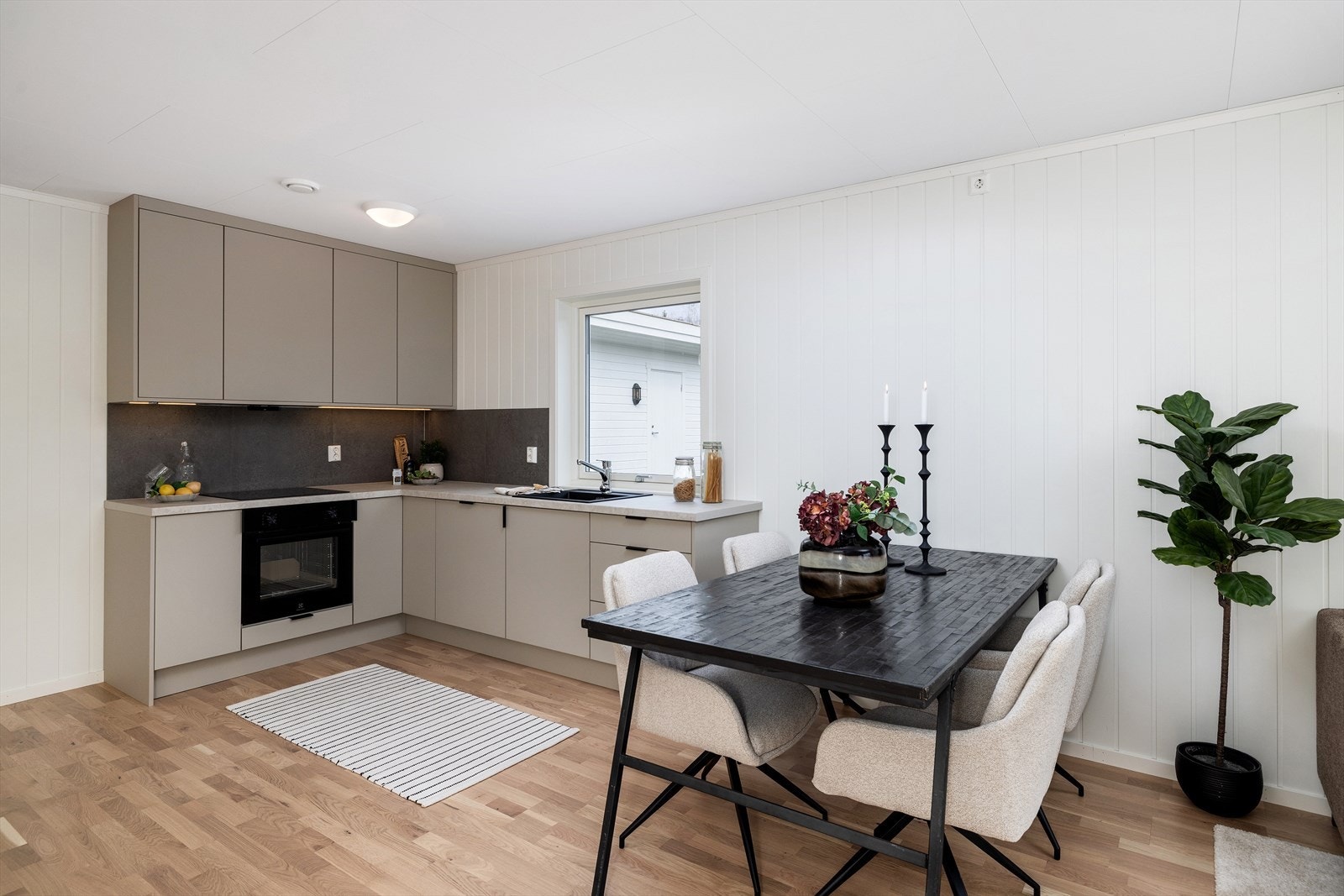 Stilrent kjøkken med integrerte hvitevarer og plass til spisegruppe i åpen løsning. Galleribilde