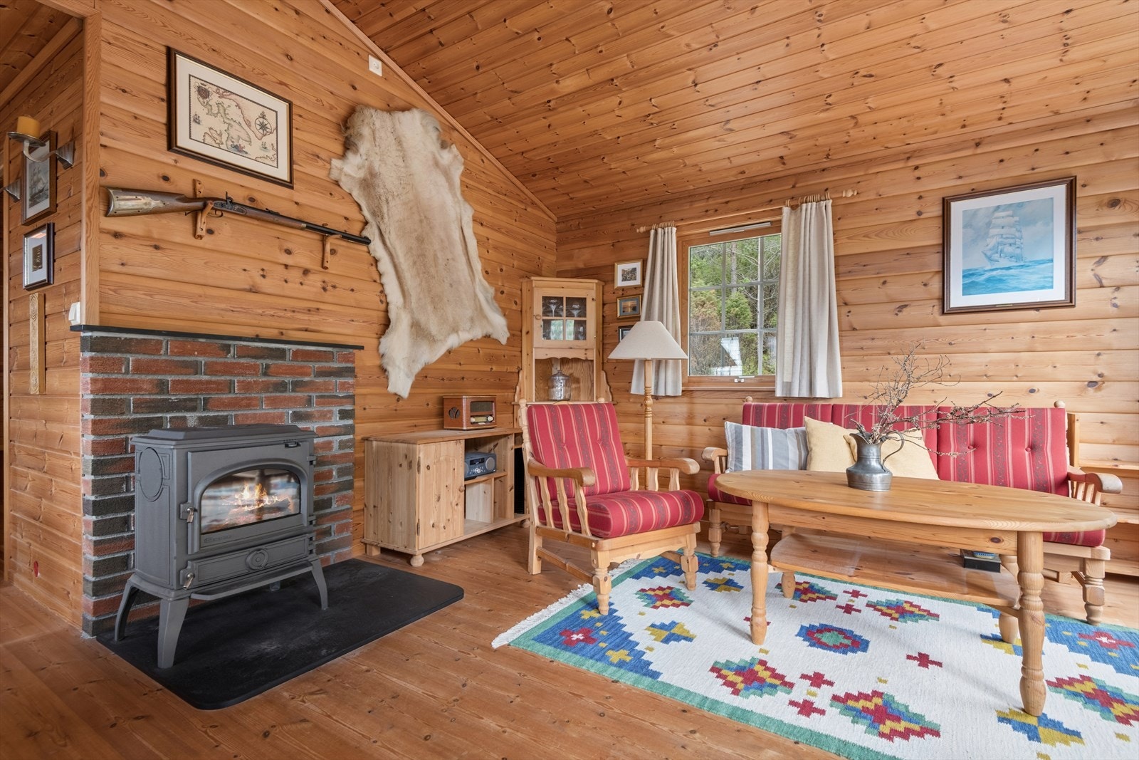 Stuen har en vedovn montert på skiferhelle, med en brannmur i teglsteinsutførelse for varme og hygge. Galleribilde