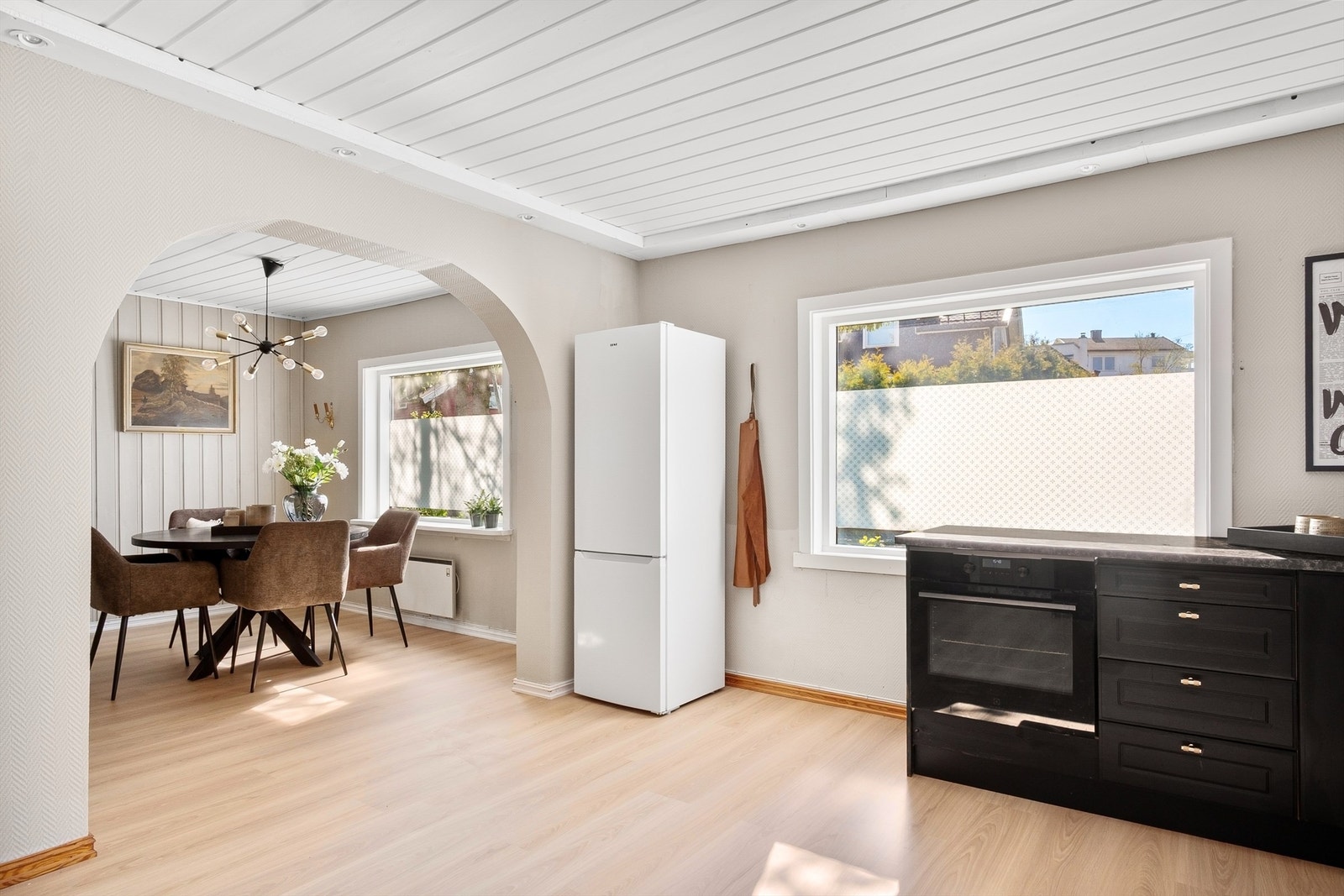 Nytt laminatgulv lagt gjennomgående mellom spisestuen og kjøkkenet skaper visuell helhet. Galleribilde
