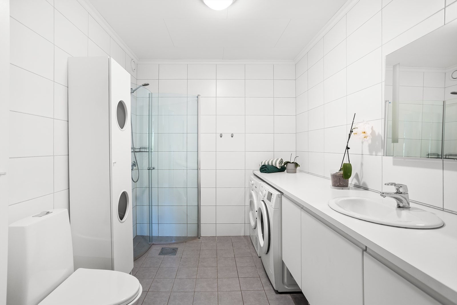 Flislagt bad med elektriske varmekabler i gulvet og opplegg for vaskemaskin. Galleribilde