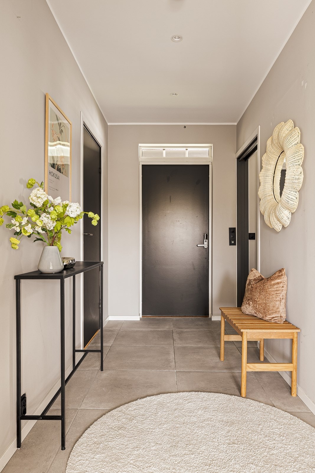 Innbydende entré med moderne design og nøytrale farger. Keramiske fliser på gulv og malt platekledning på vegger. Malt platekledning i himling med innfelte spotlights. Galleribilde