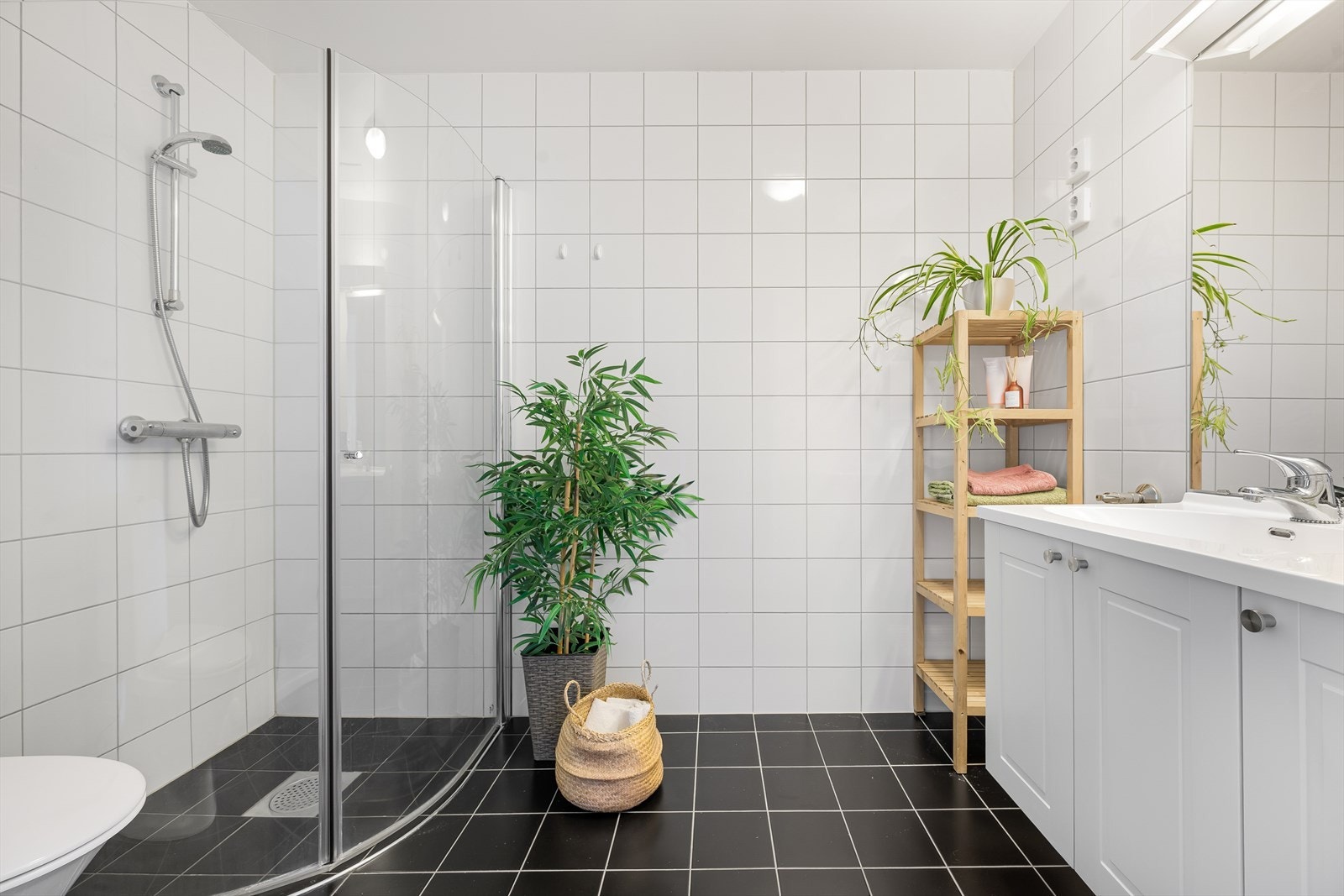 Badet fremstår funksjonelt og stilrent med innfellbare dusjvegger i herdet glass, helservant på innredning, klosett, gulvvarme og praktisk opplegg for vaskemaskin og tørketrommel. Galleribilde
