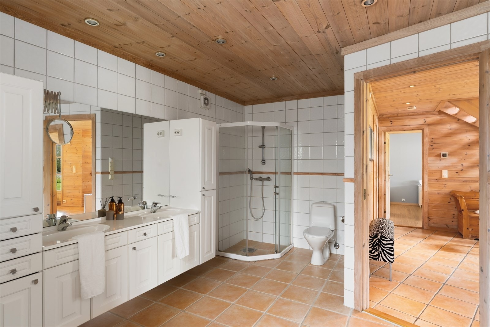 Badet har innredning med dobbel servant, dusjhjørne, innebygget hjørnebadekar og toalett. Galleribilde