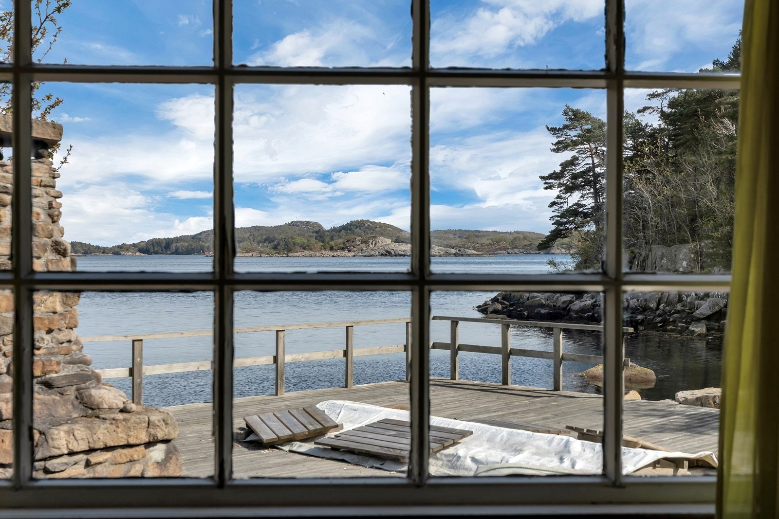 Vinduet rammer inn utsikten mot terrassen og sjøen. Galleribilde
