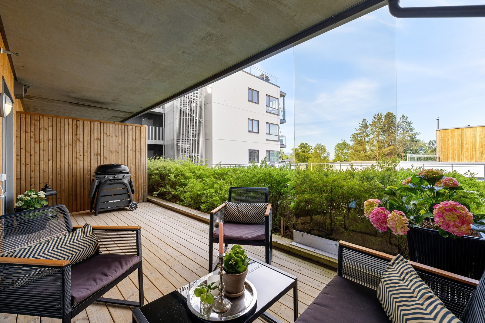 En stor og frodig hekk foran terrassen begrenser innsynet i leiligheten. Galleribilde