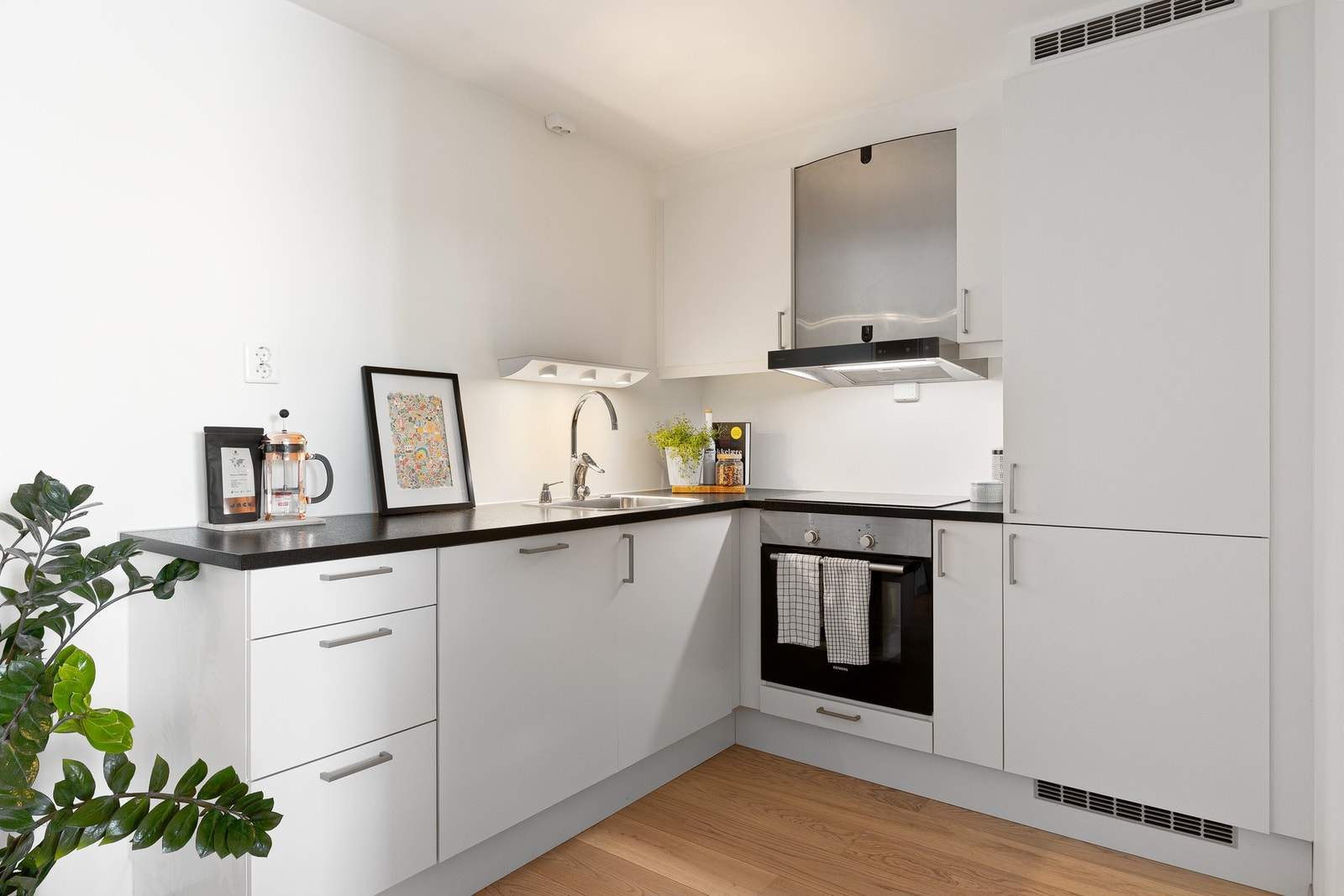 Leilighetens kjøkken fremstår som både lyst og moderne, med integrerte hvitevarer som inkluderer platetopp, stekeovn, kjøle/fryseskap og oppvaskmaskin. Galleribilde