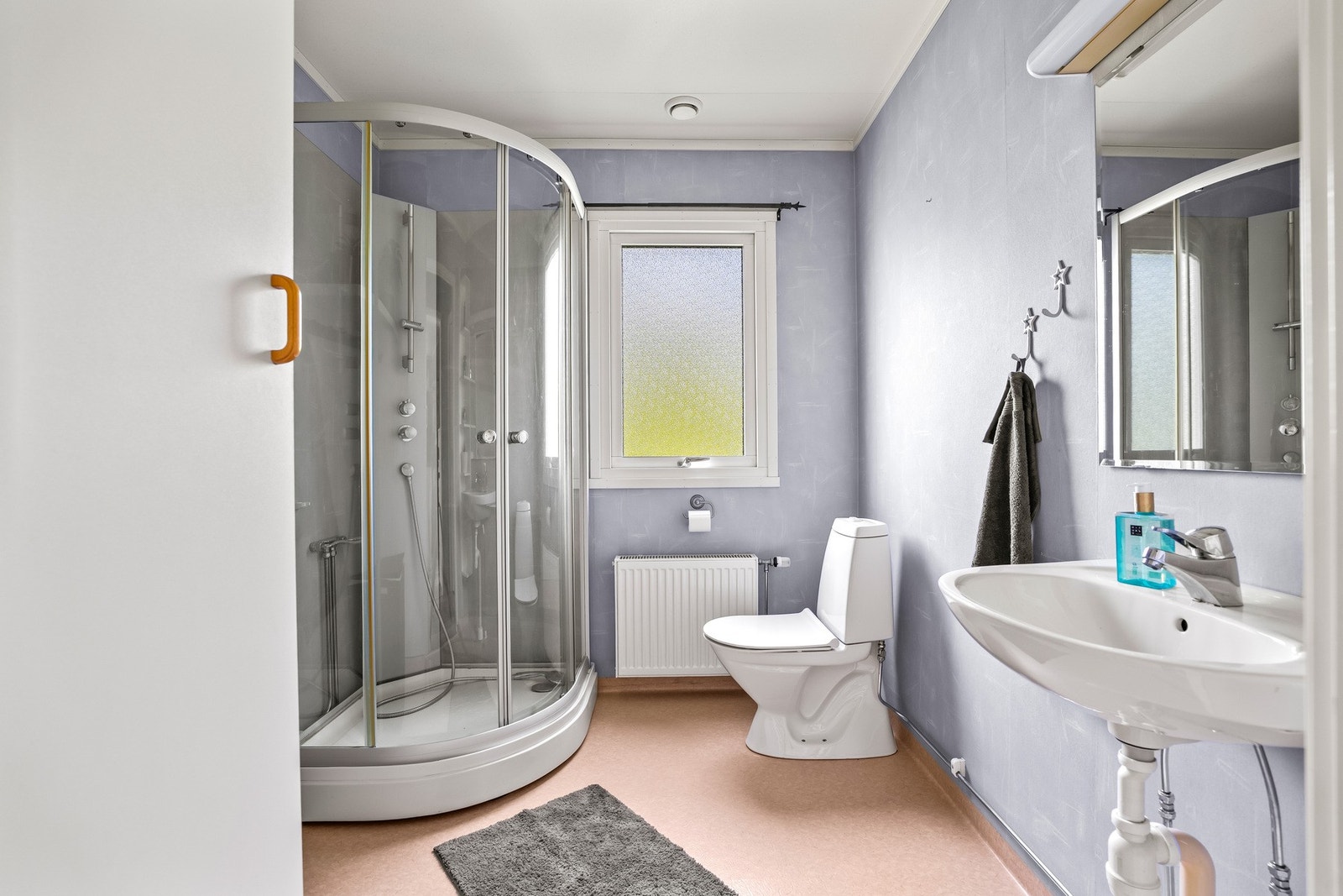Badet i første etasje er utstyrt med toalett, veggmontert servant med speil og belysning, samt dusjkabinett i herdet glass. Galleribilde